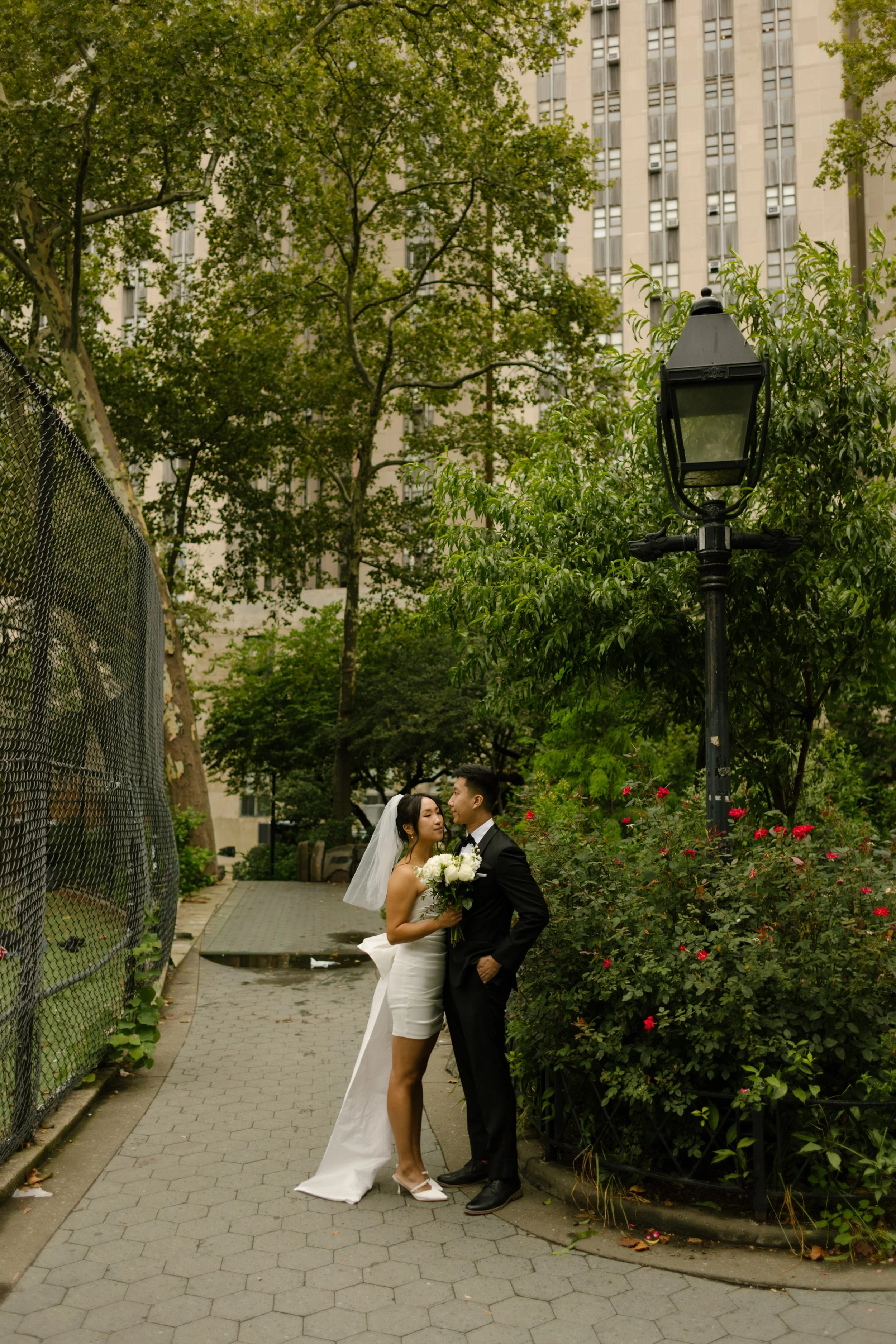 Couple kisses beneath trees in a Lower Manhattan park after their intimate courthouse wedding.