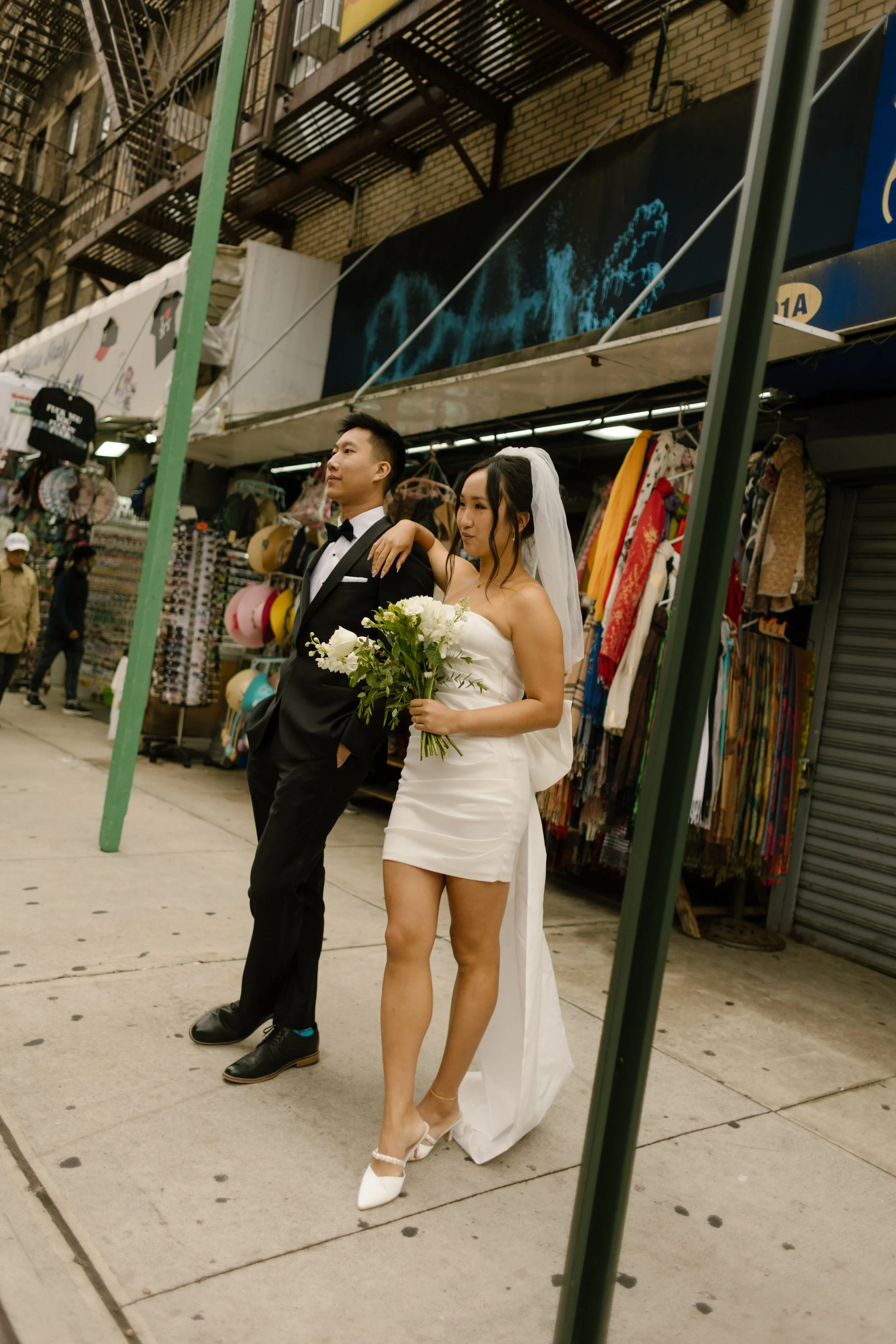 Newlyweds stroll through Chinatown with bouquet in hand after their nyc courthouse wedding.