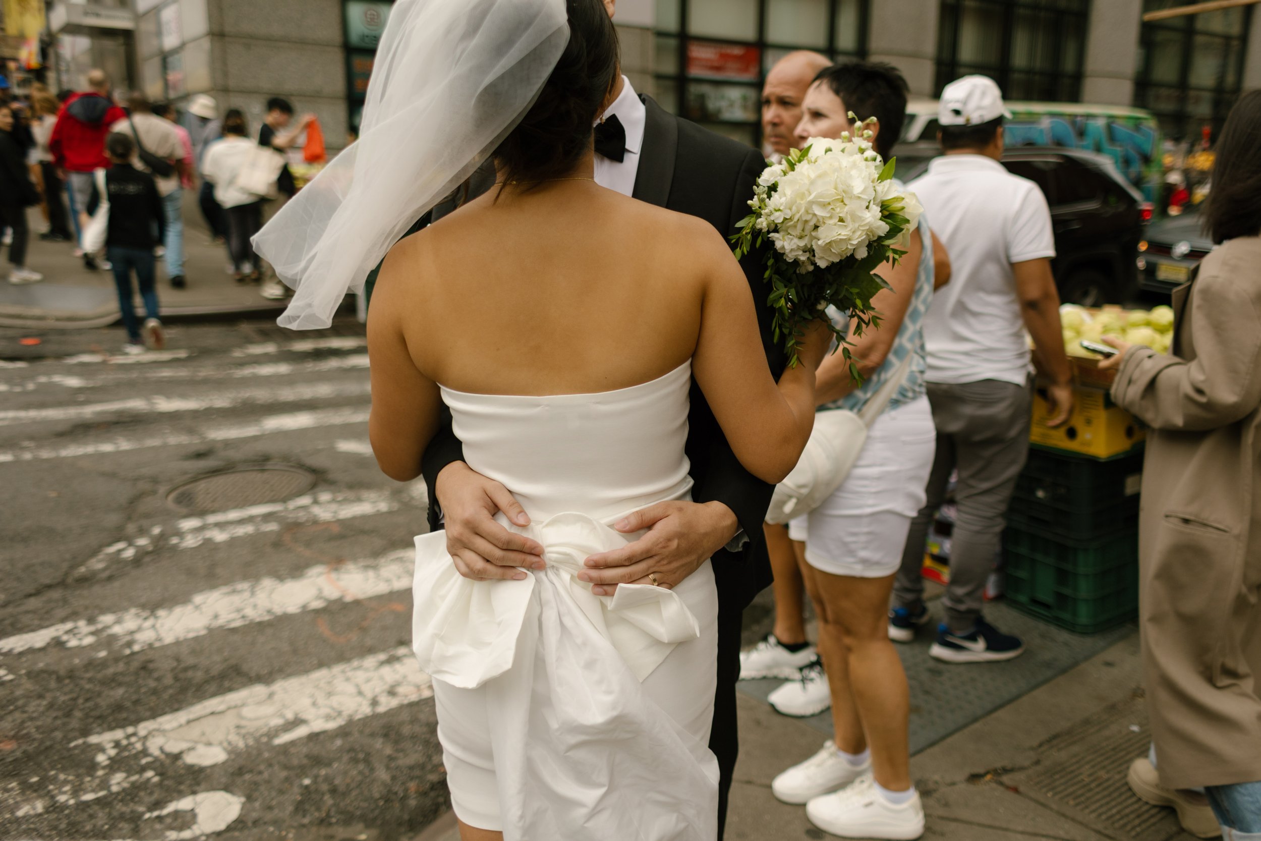 Bride and groom embrace on a busy Manhattan street after their nyc courthouse wedding, surrounded by the energy of Chinatown.