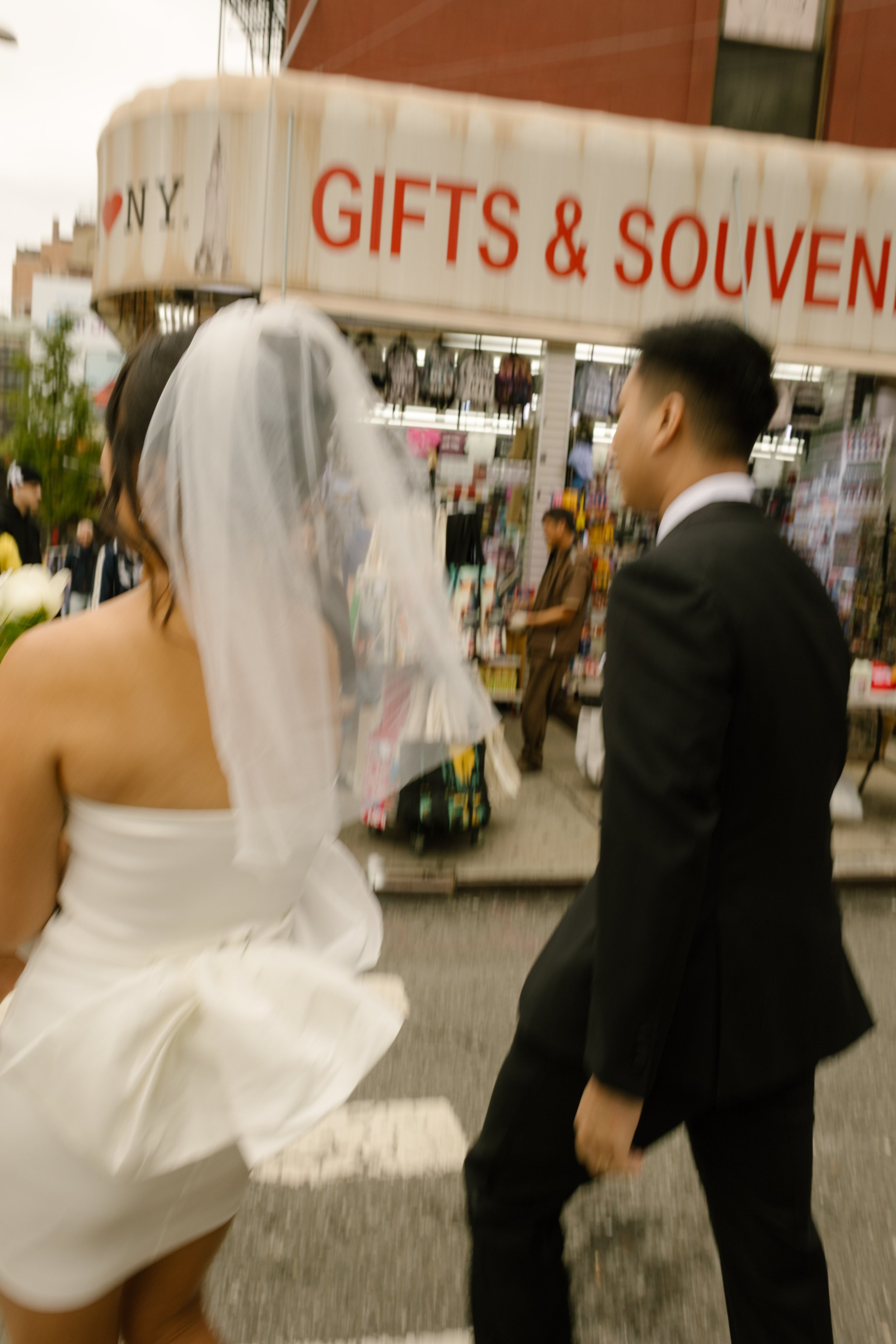Motion-blur photo of a couple walking through Little Italy after their New York City courthouse wedding.