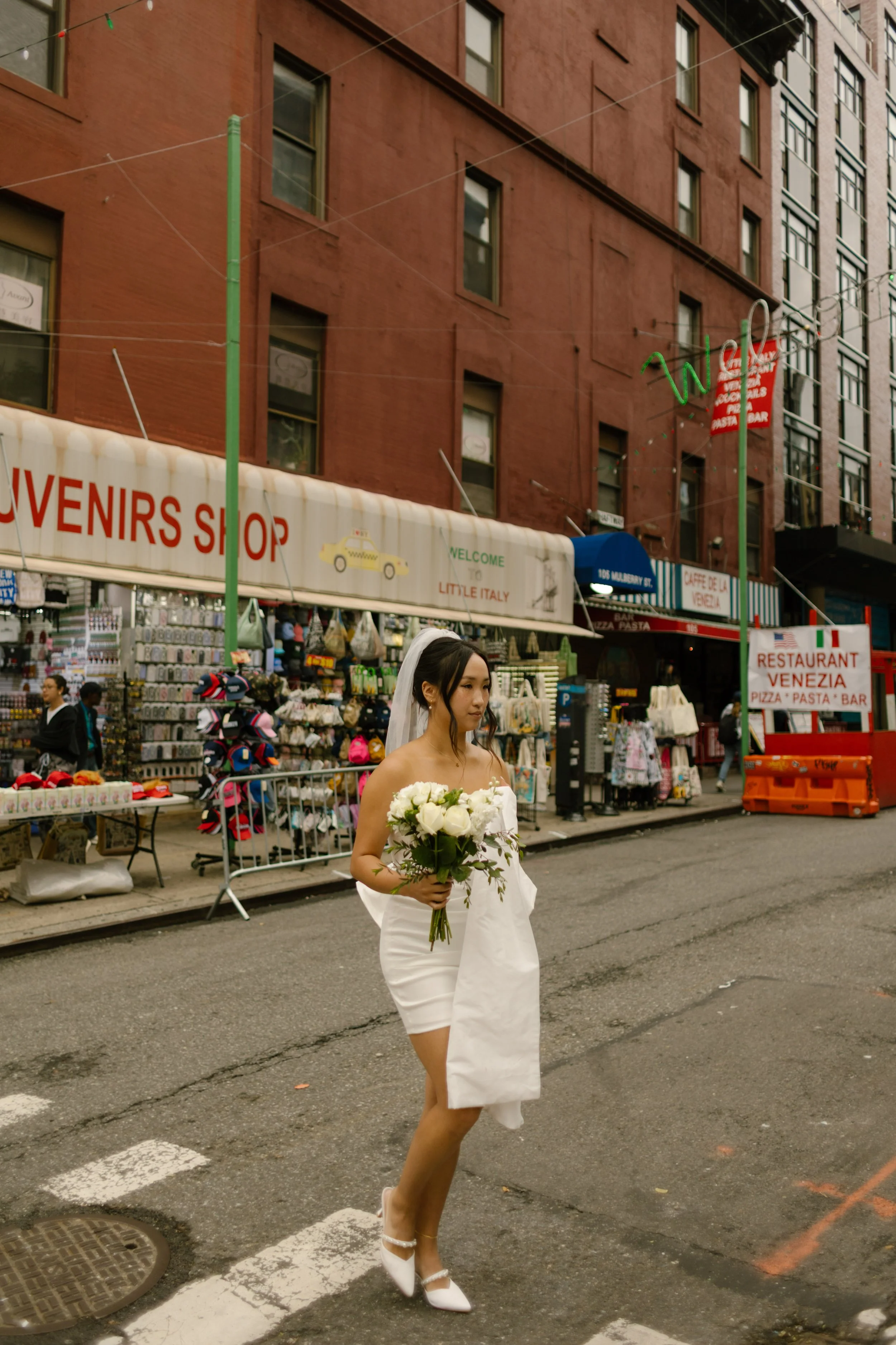 Bride walks through Little Italy with bouquet in hand after her nyc courthouse wedding.