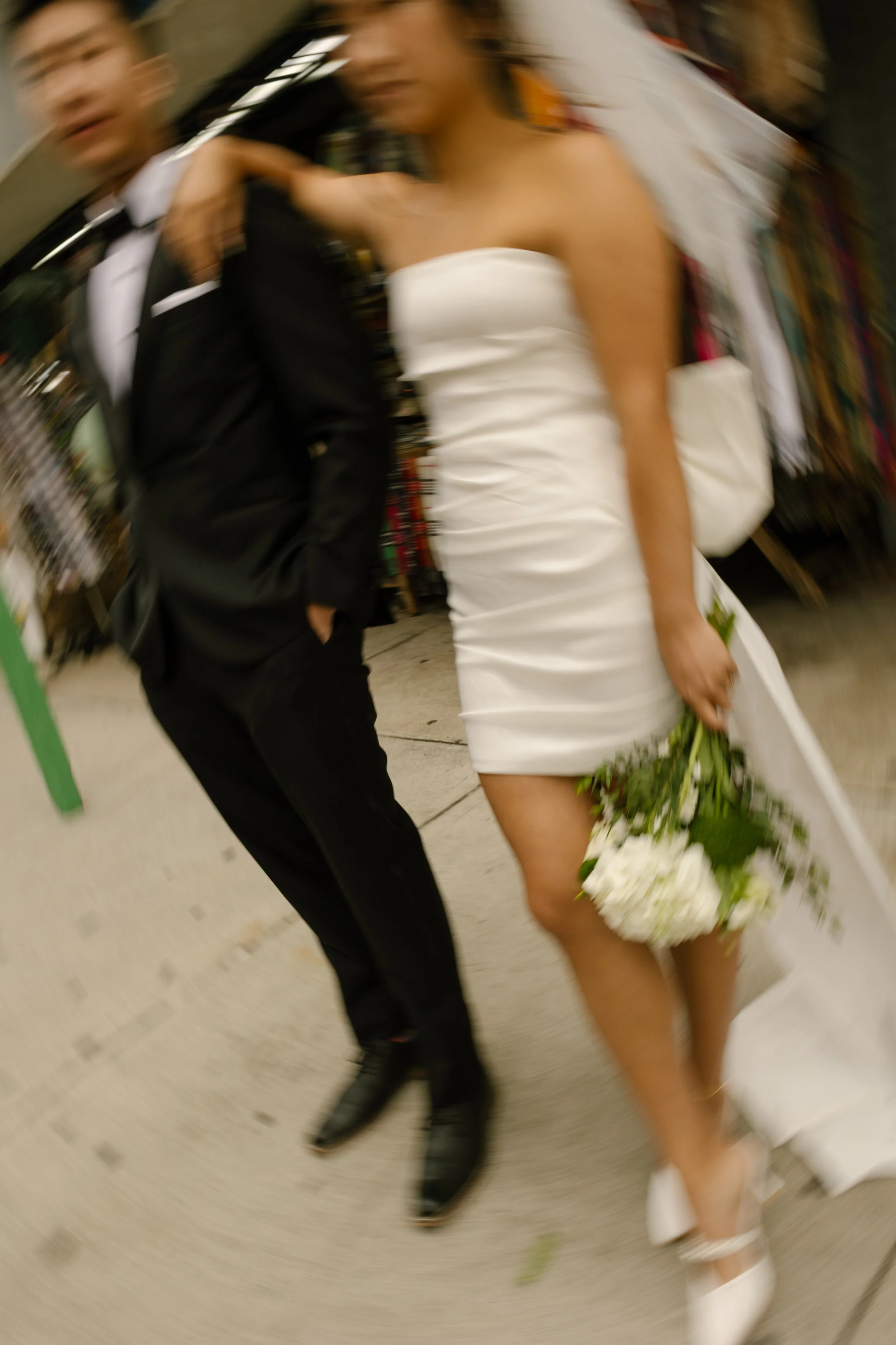 Motion-blur portrait of a couple walking through Chinatown after their nyc courthouse wedding.