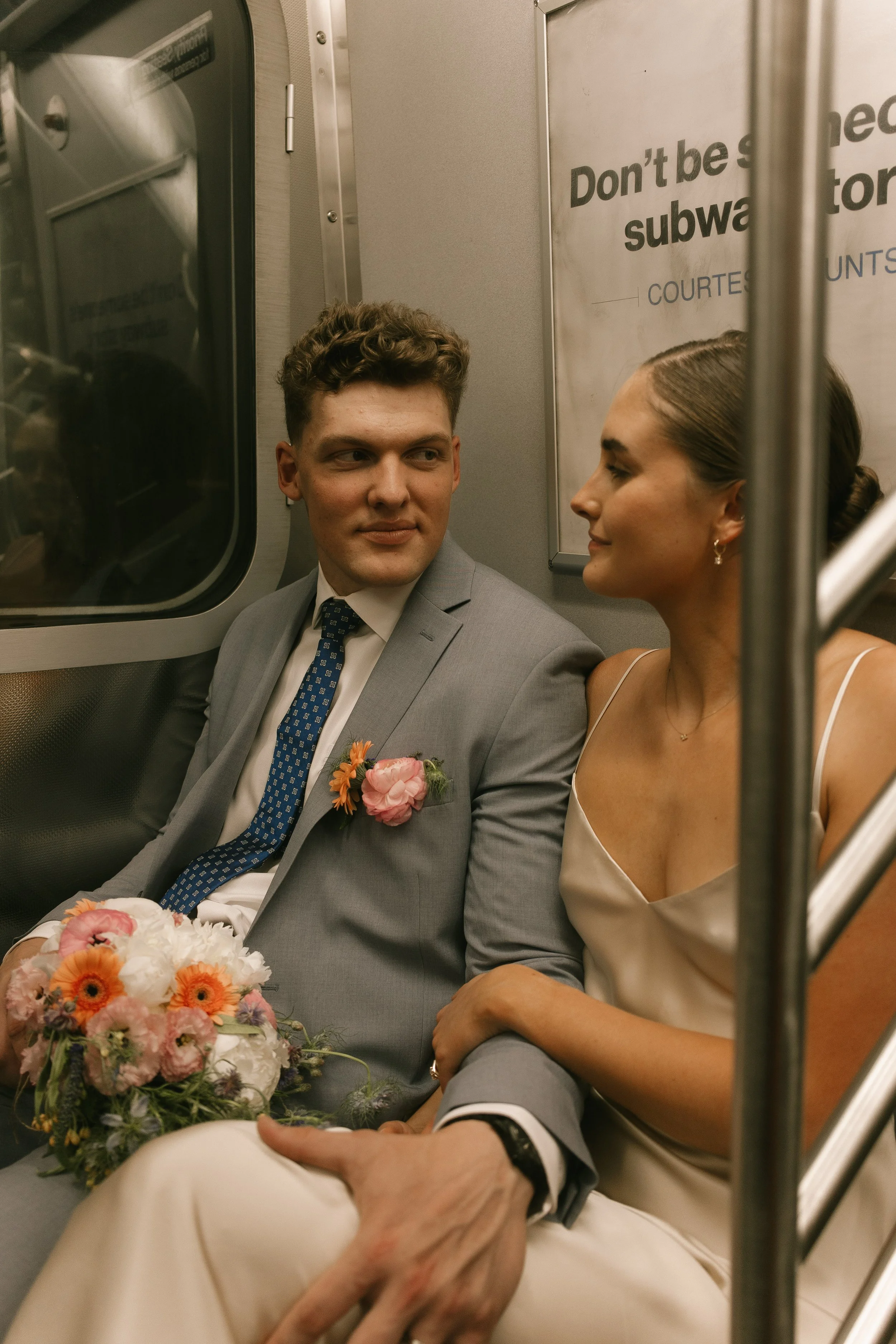 Newlyweds sitting together on a subway train during a unique New York City wedding portrait session.