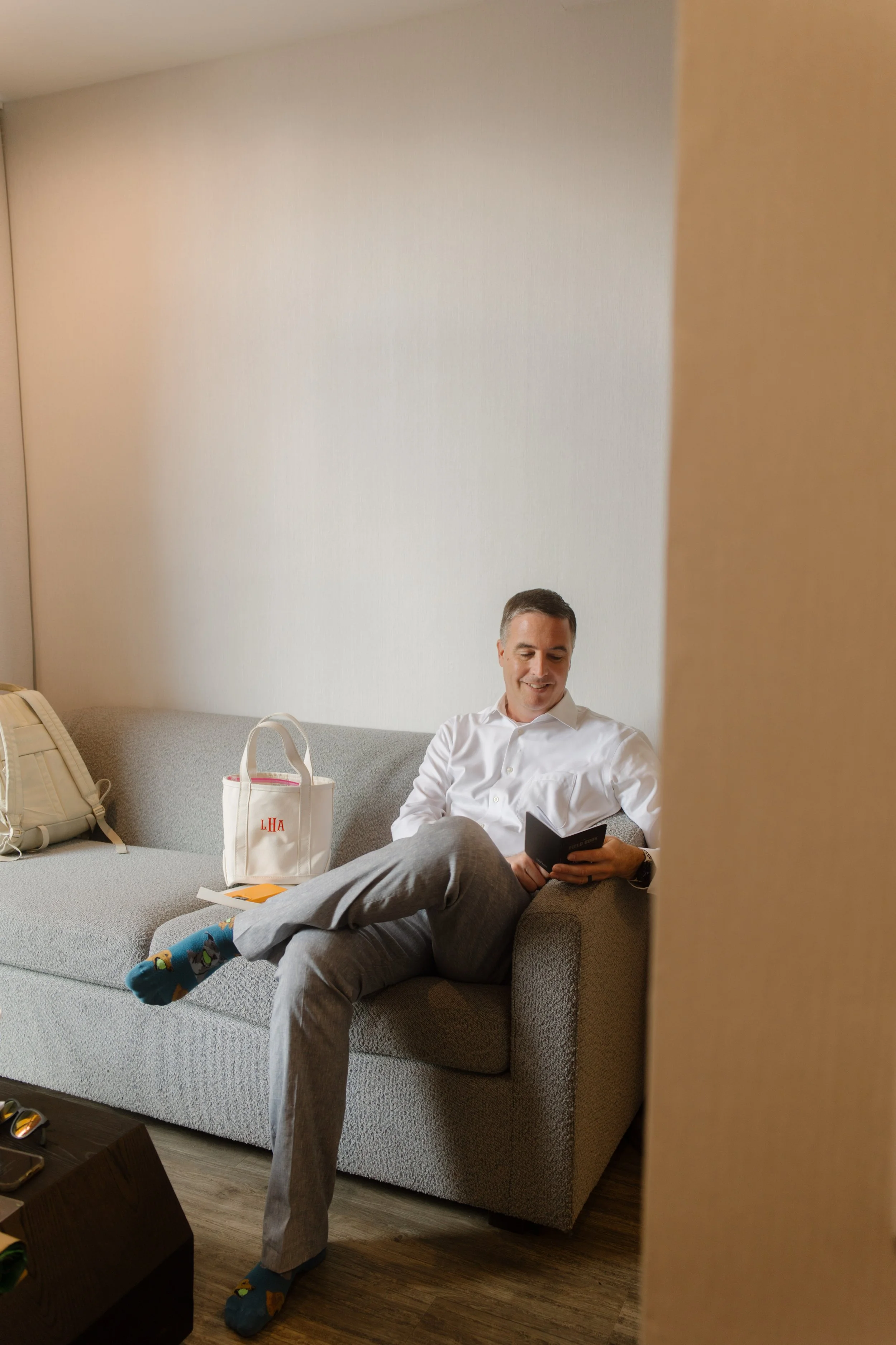 Groom relaxing before the ceremony in a hotel suite, an important part of a well-planned wedding day timeline.