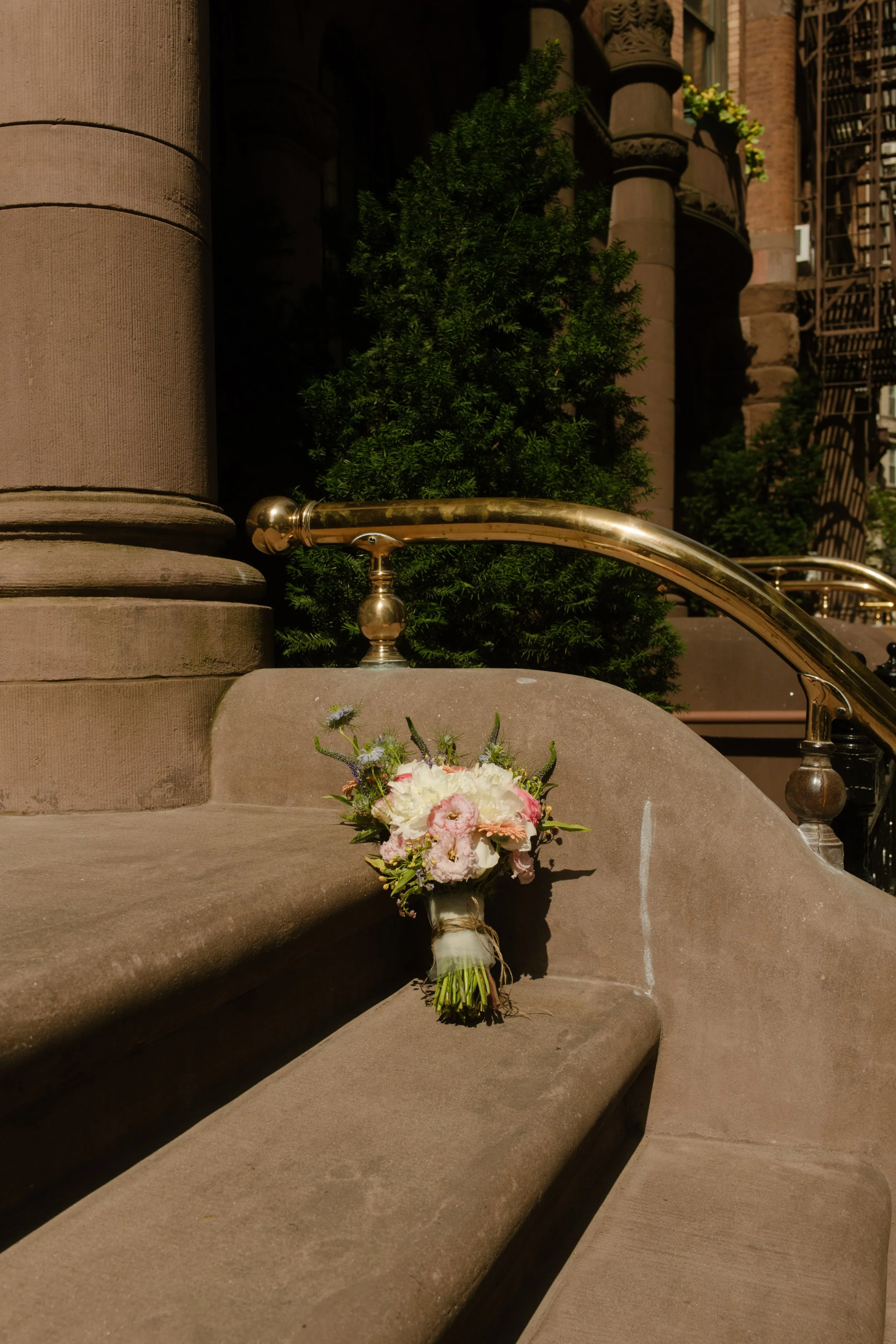 Bridal bouquet resting on classic New York brownstone steps before portraits begin.
