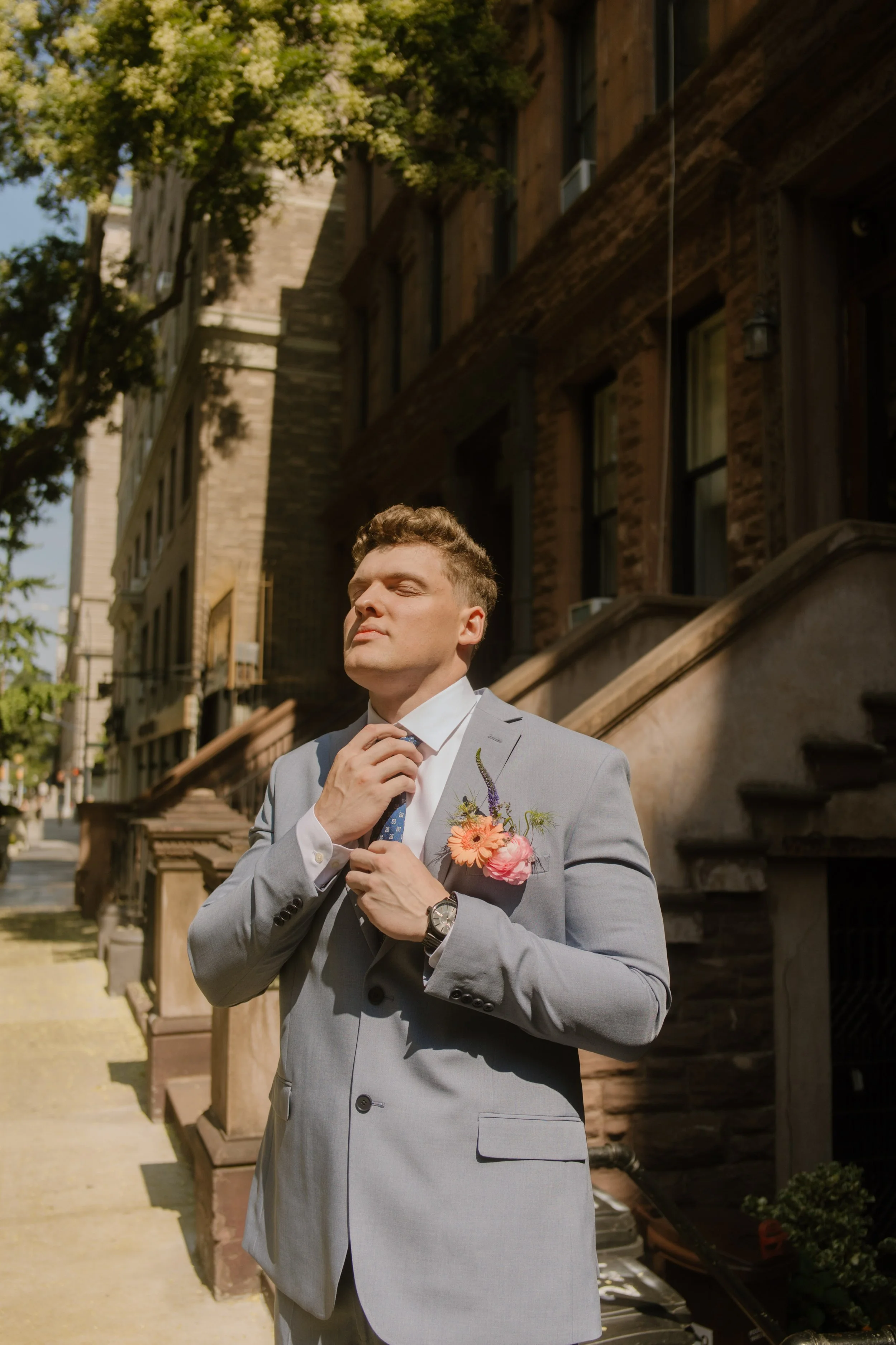Groom adjusting his tie outside a New York brownstone before the ceremony.