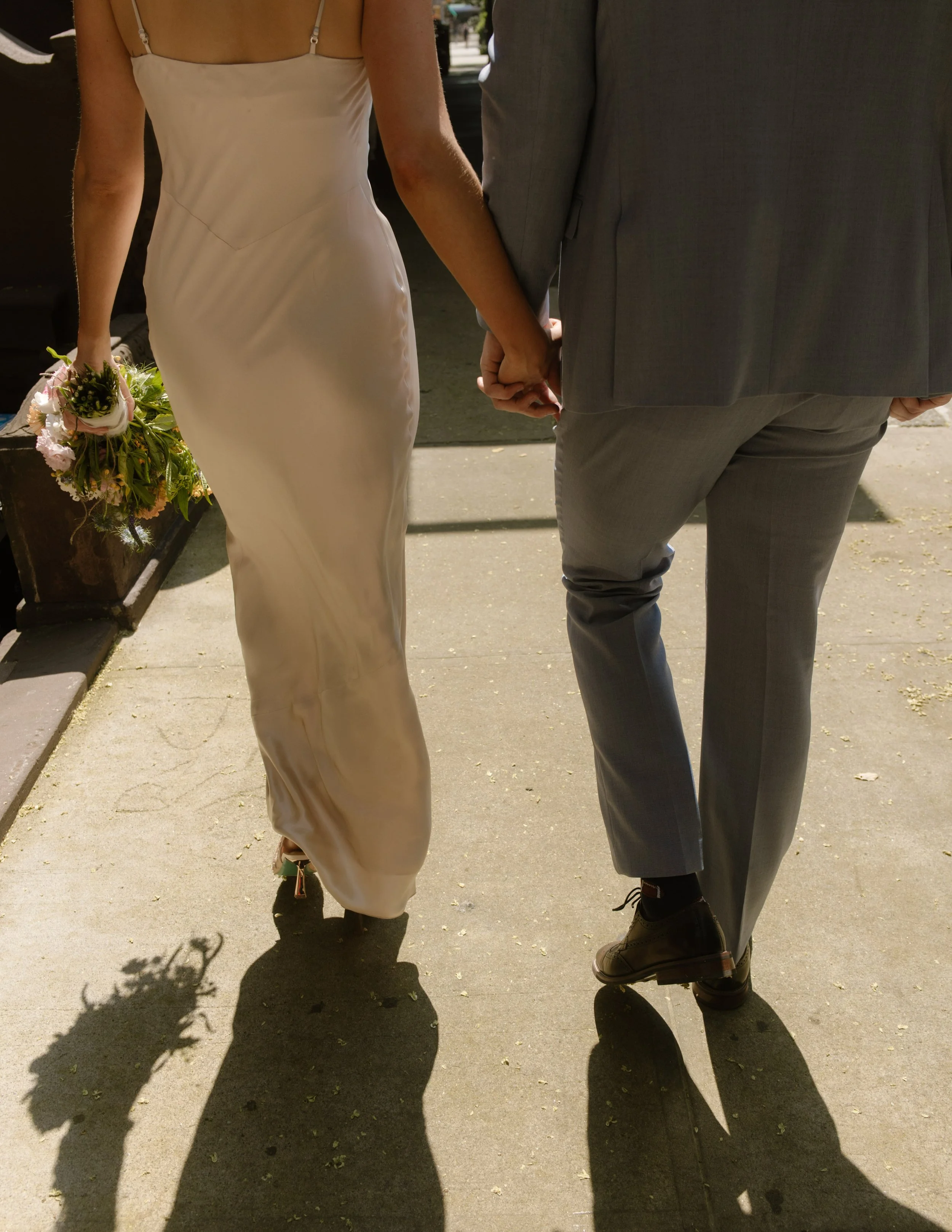 Close-up of the bride and groom holding hands while walking between portrait locations.