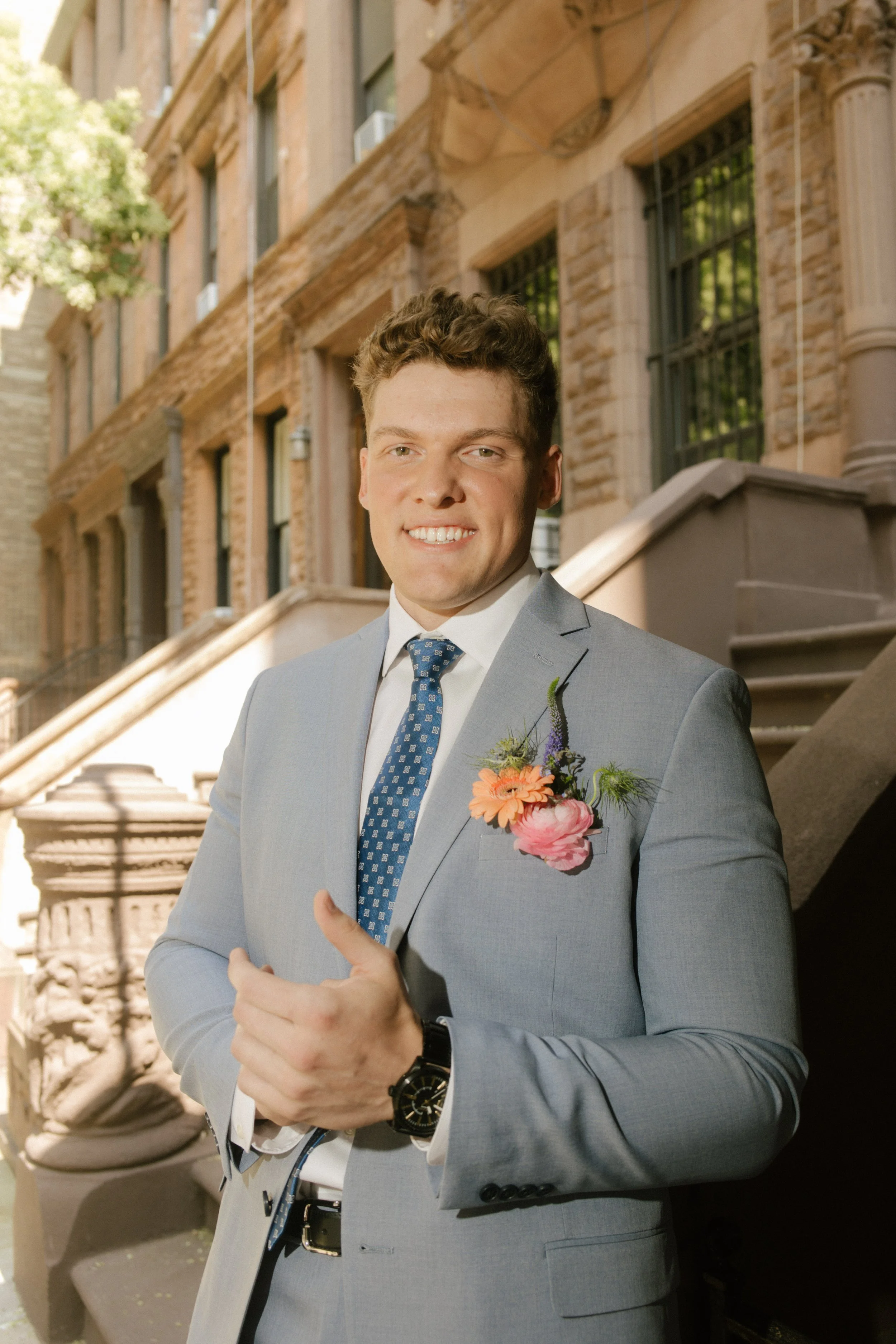 Groom adjusting his jacket outside a New York brownstone before the ceremony, an important part of the wedding day timeline.