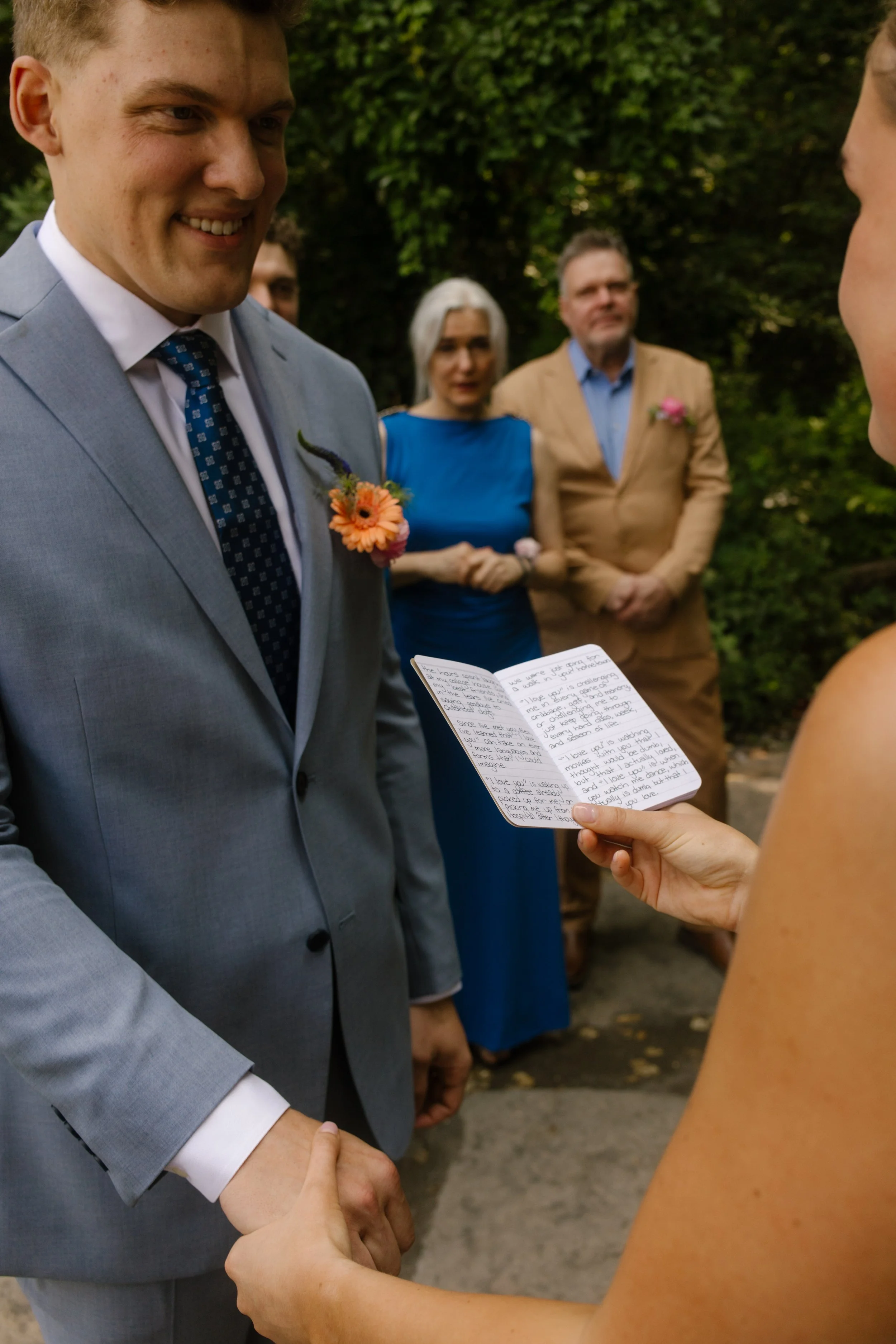 Bride reading handwritten vows while holding the groom's hand during the ceremony.