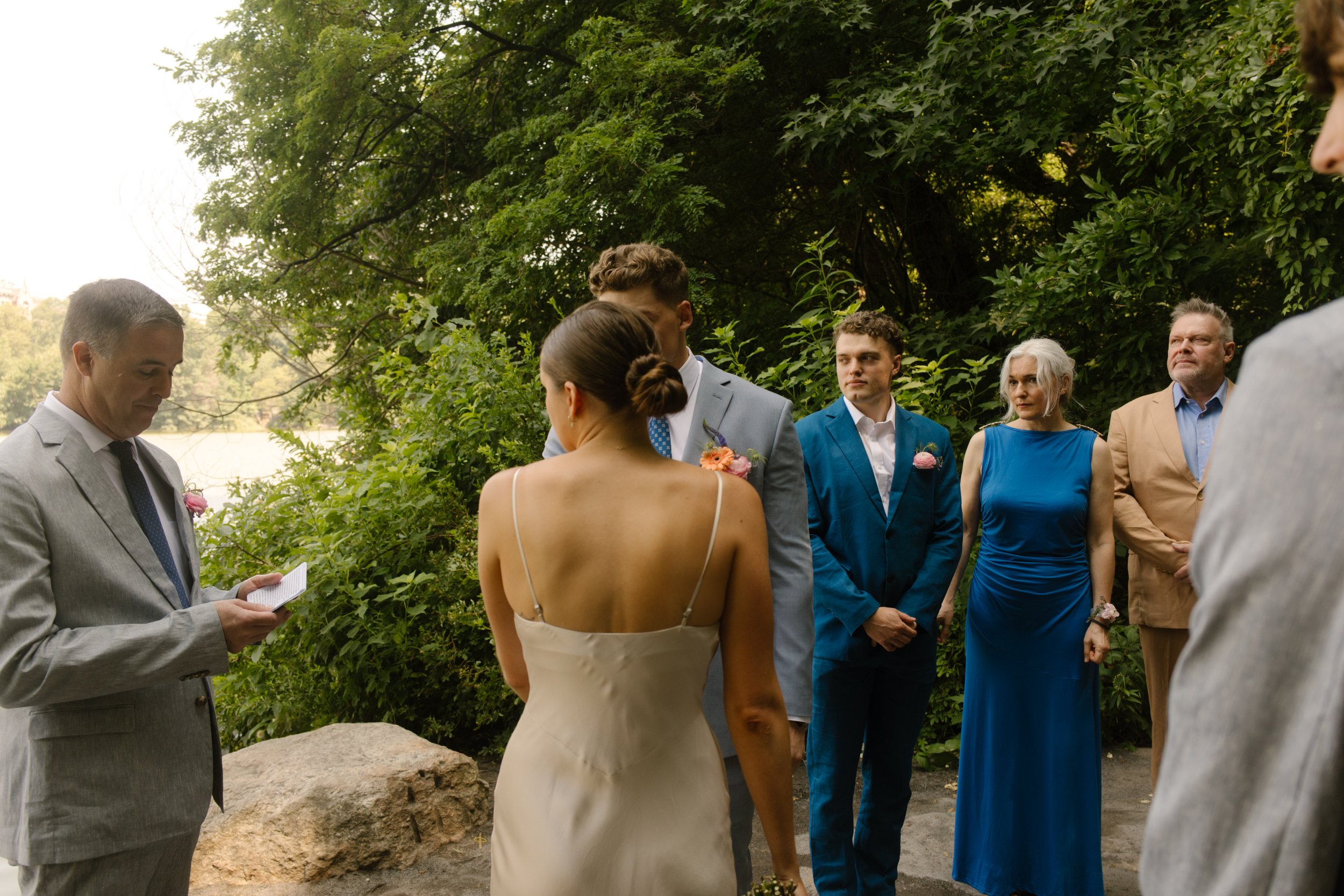 Bride standing with family as the officiant leads the lakeside ceremony in Central Park.