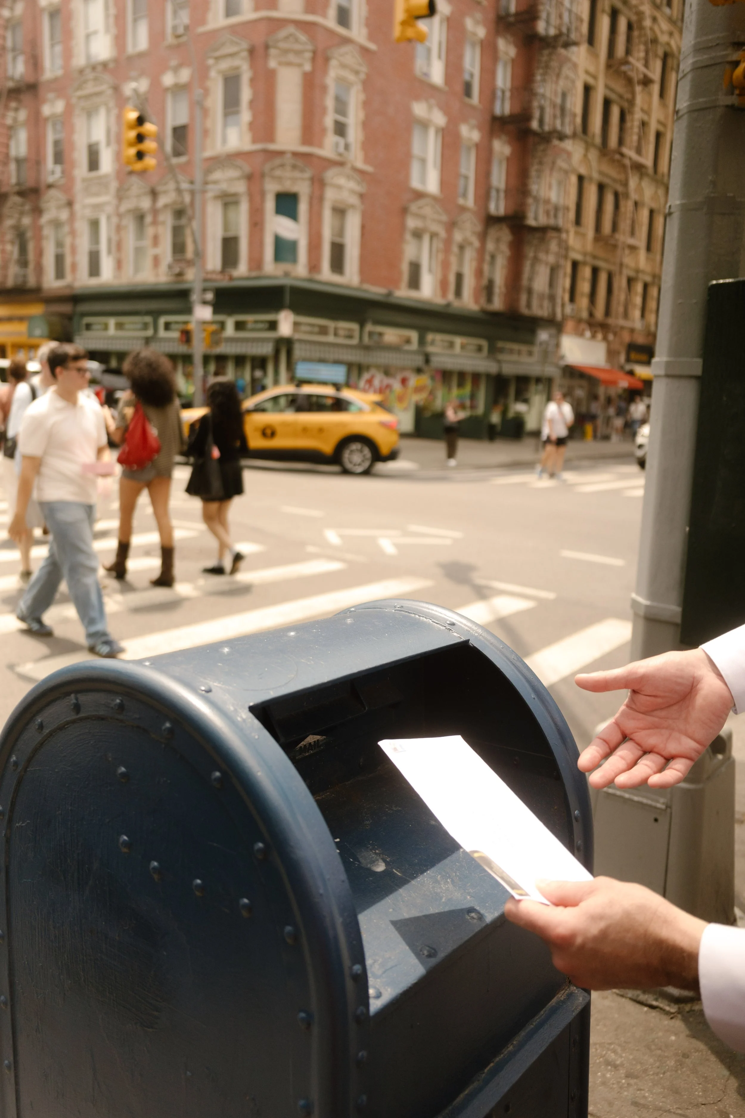 Groom mailing a postcard on a New York City street as a unique wedding day keepsake.