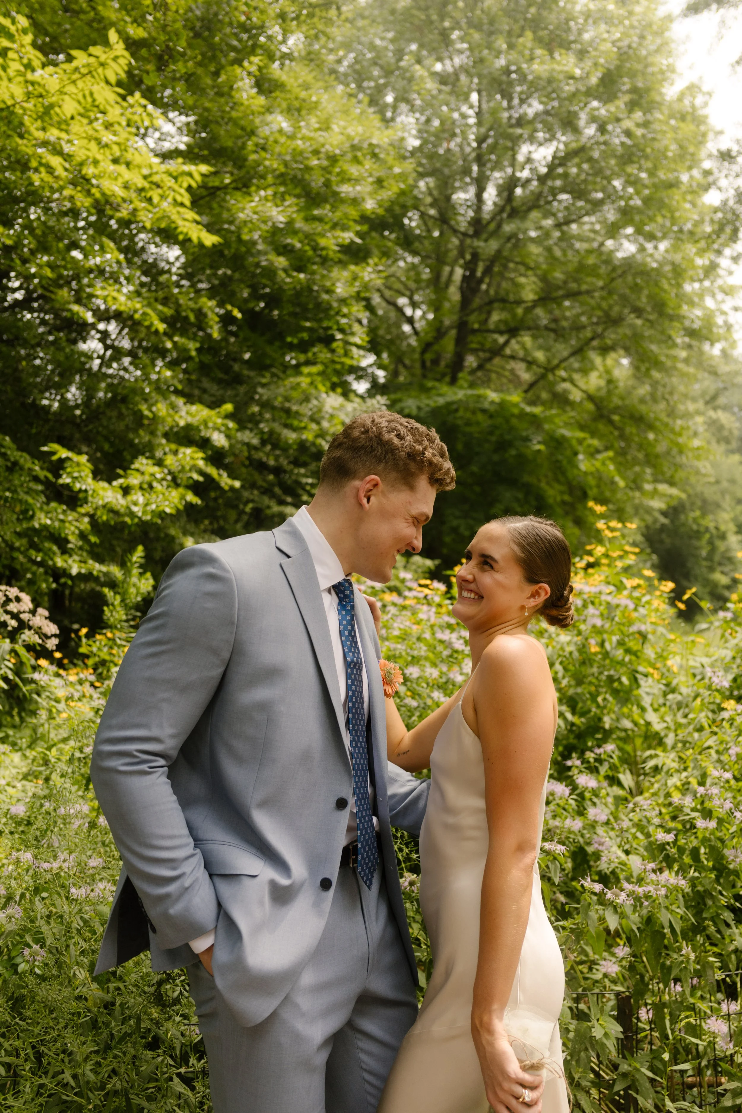 Bride and groom smiling together in a wildflower garden during their wedding day timeline portraits.