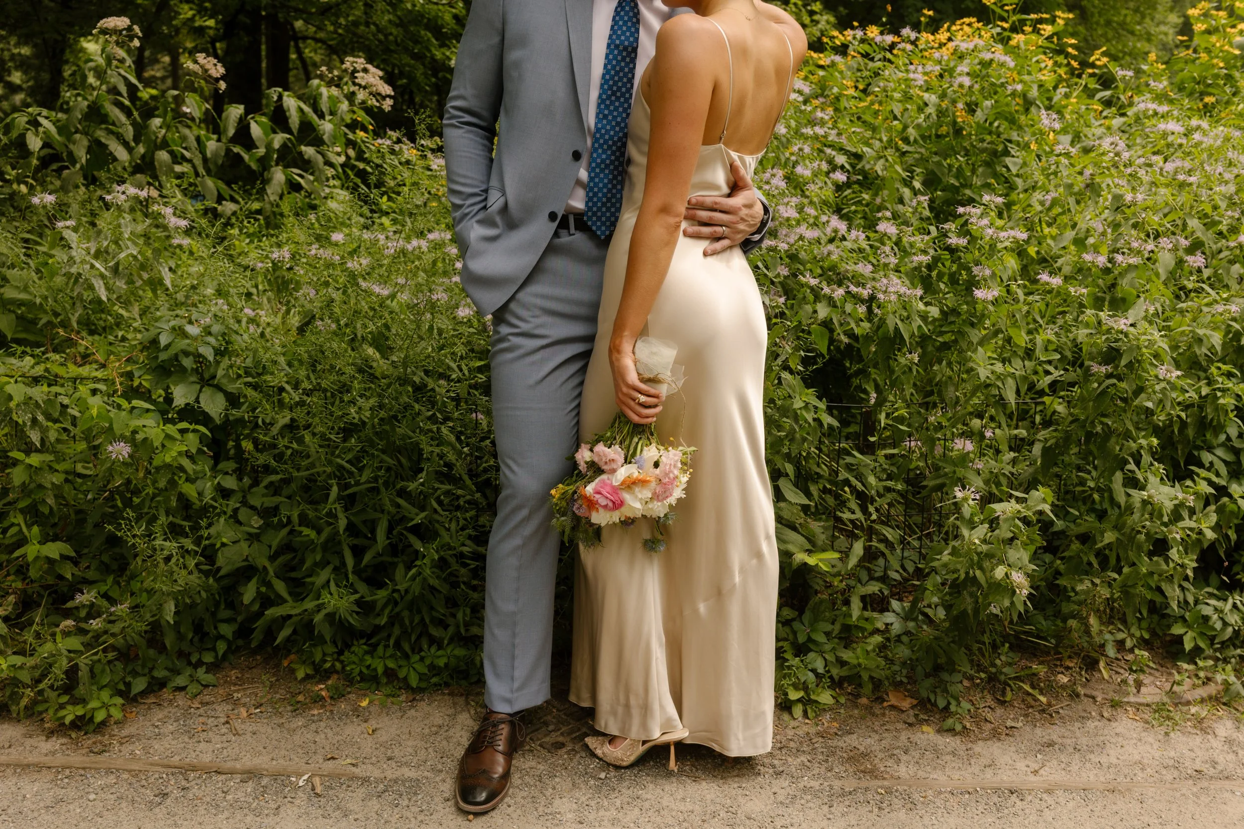 Romantic close-up of the bride holding her bouquet while embracing the groom in Central Park.