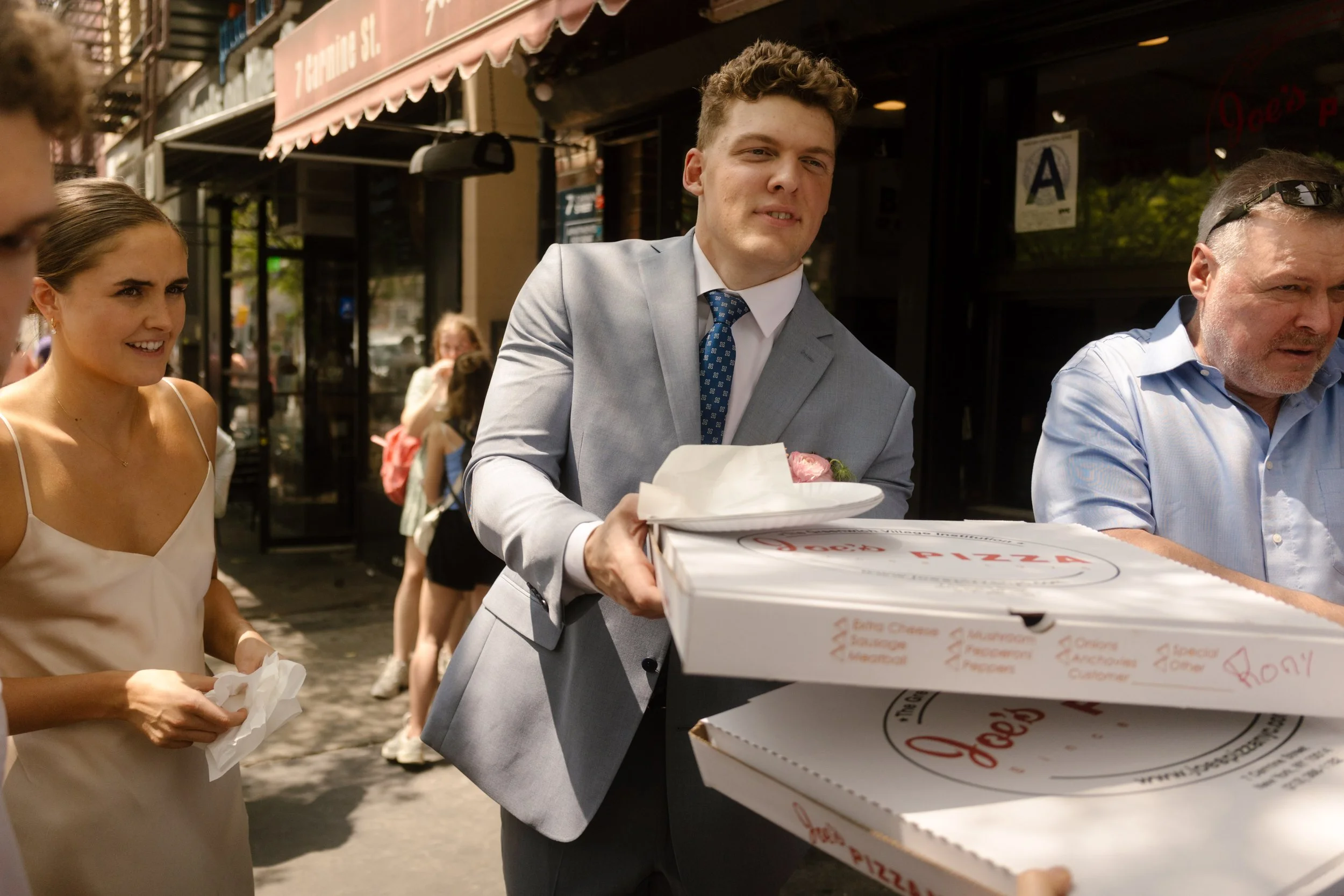 Groom handing out pizza boxes to friends after the wedding ceremony.