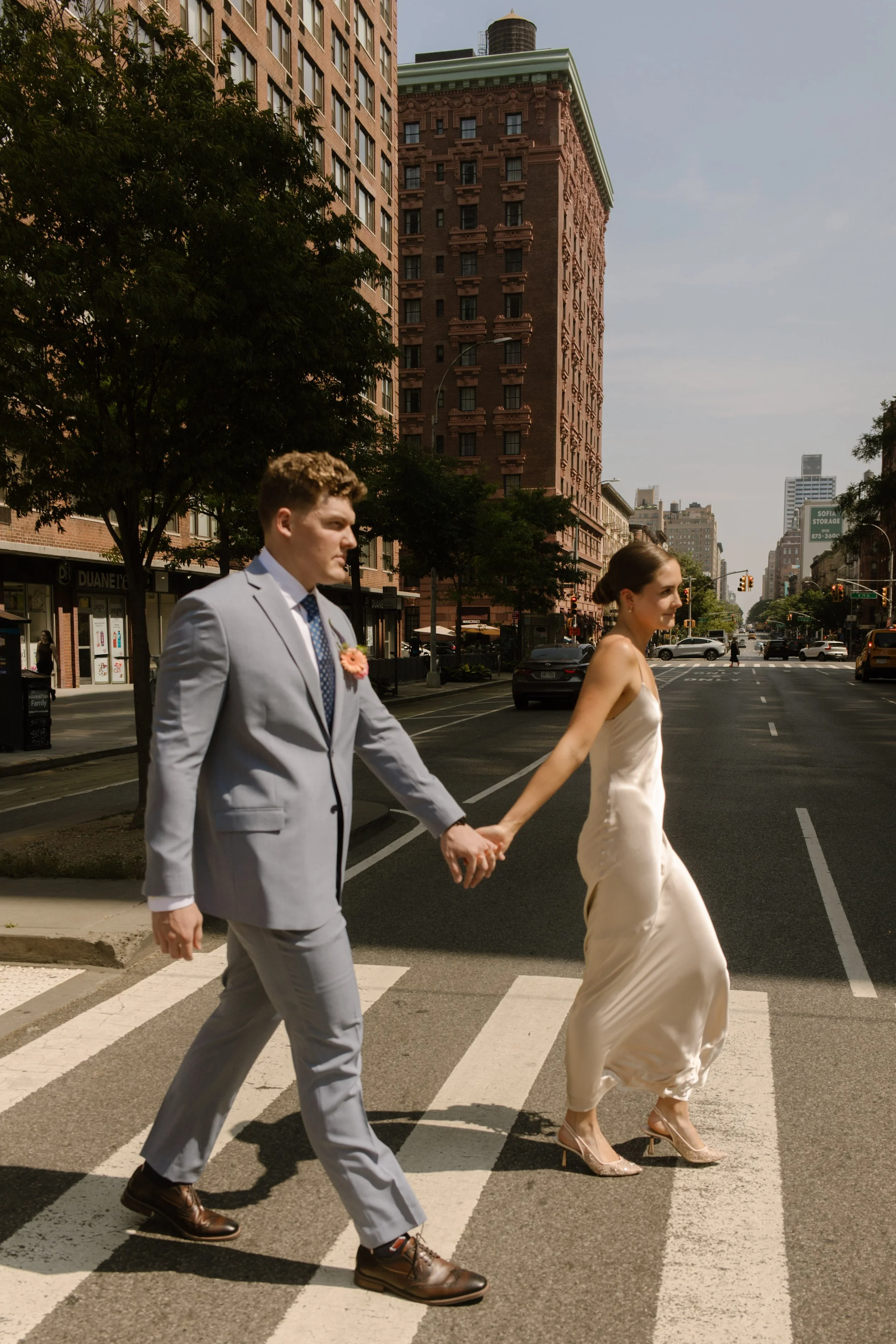 Bride and groom holding hands while crossing a Manhattan street during their wedding day timeline portraits.