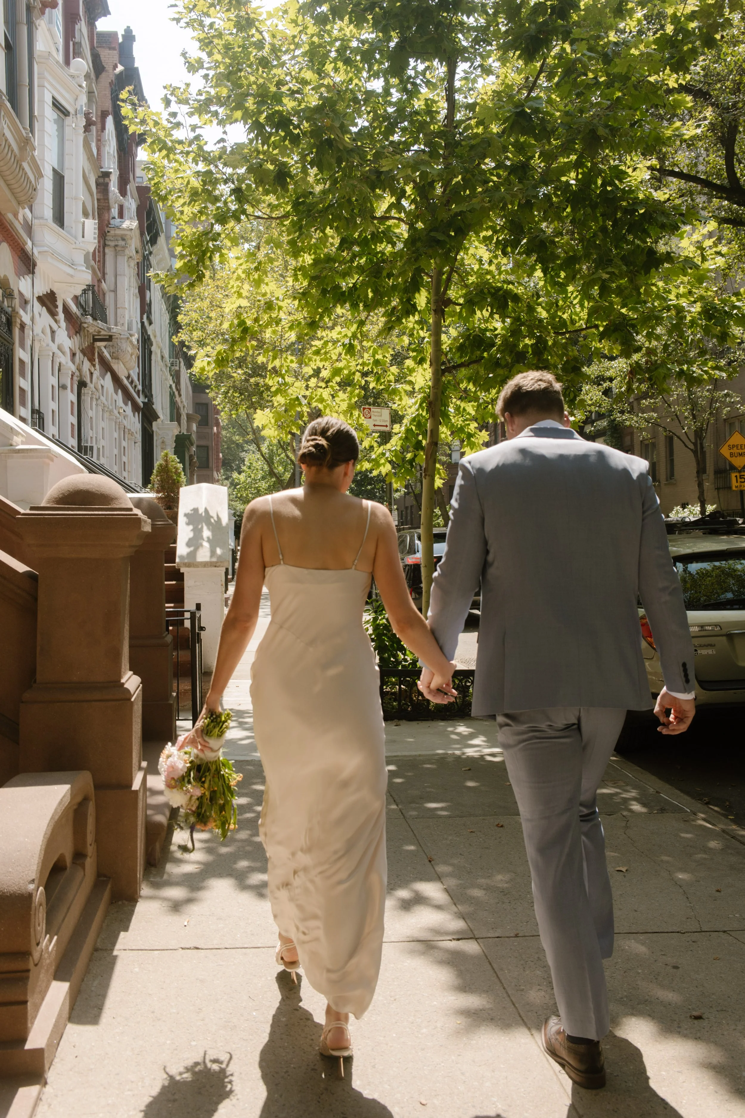 Bride and groom holding hands while crossing a New York City crosswalk during their wedding day timeline portraits.