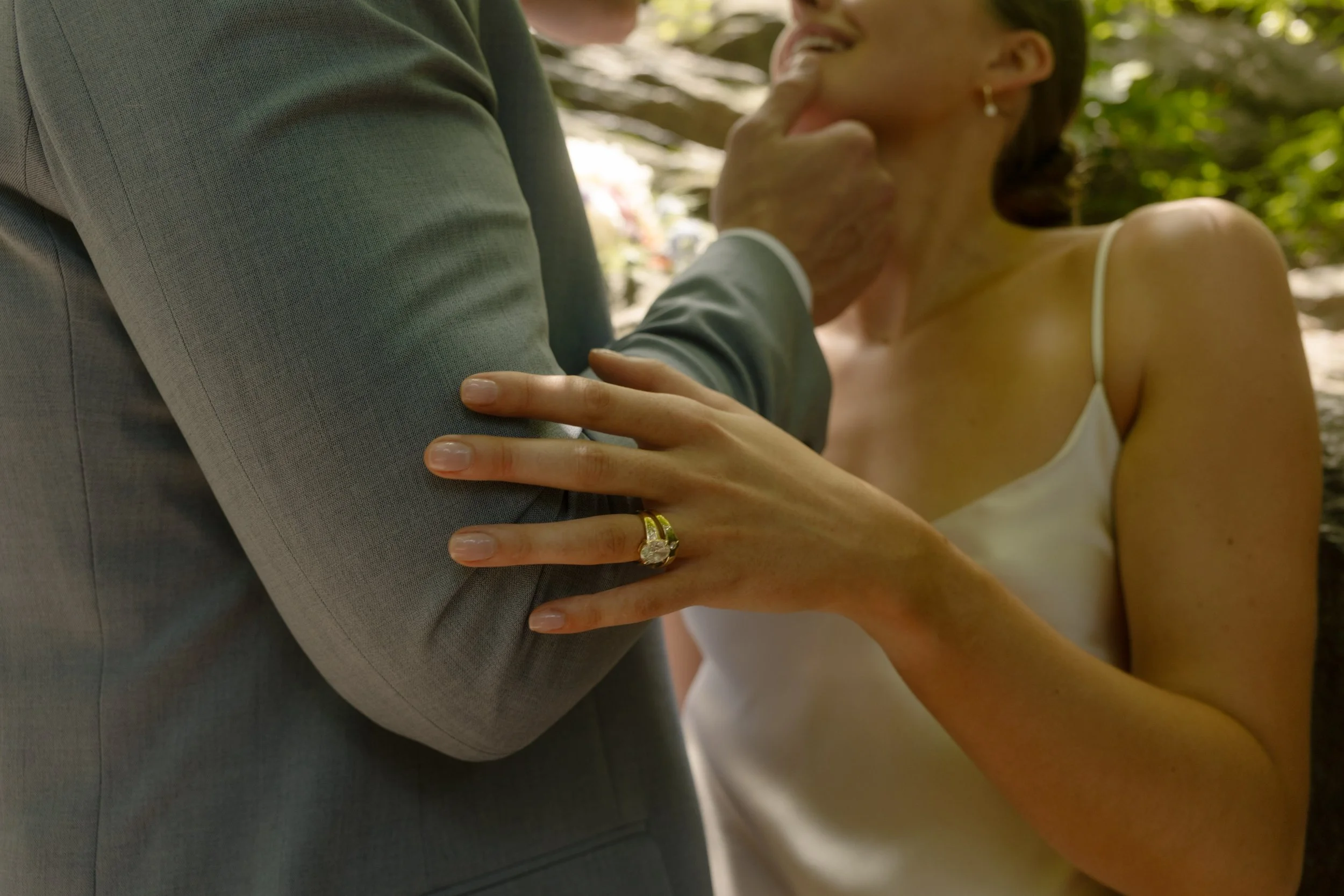 Close-up of the bride's diamond engagement ring as she embraces her groom.