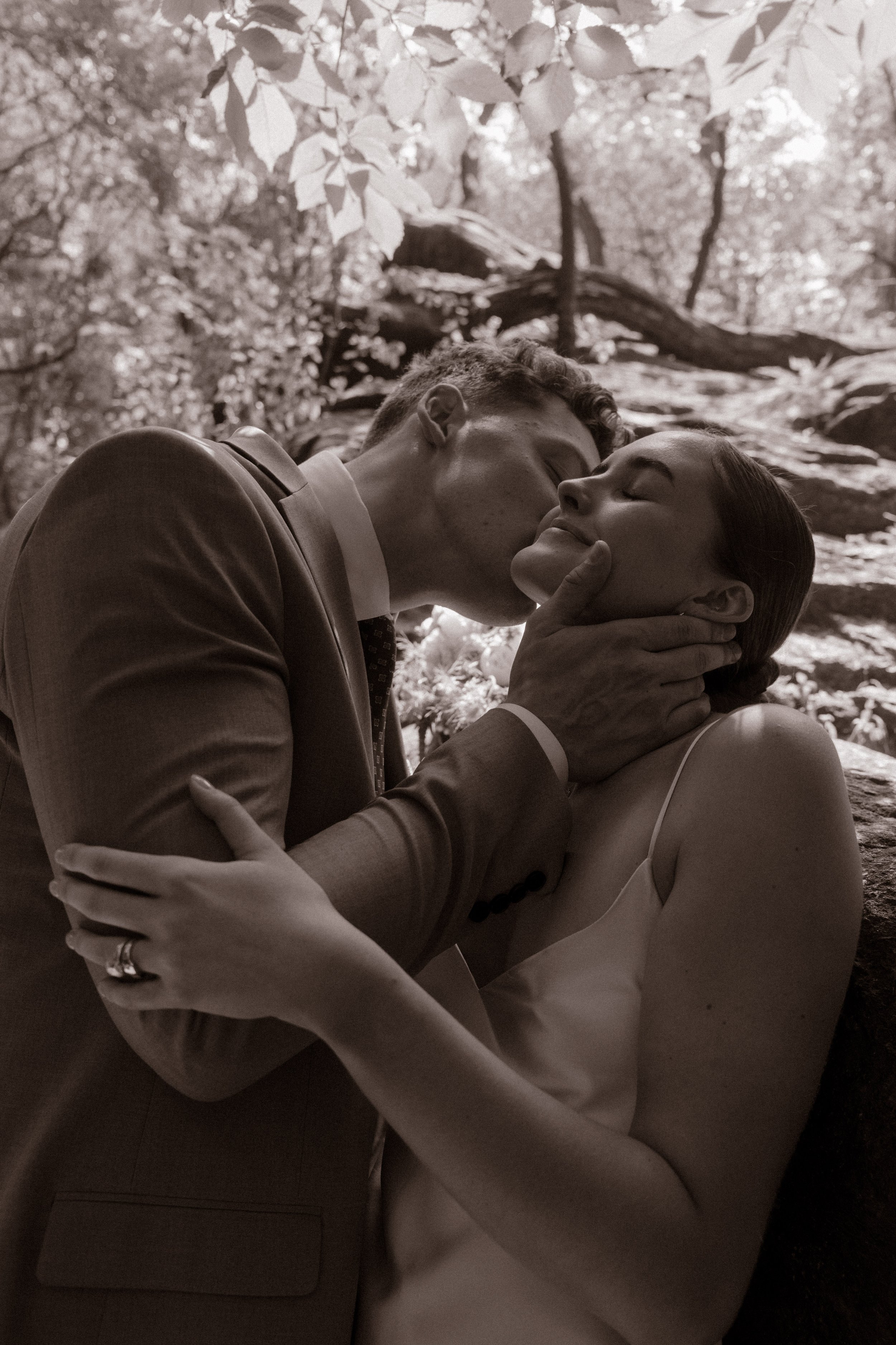 Black-and-white close-up of the groom kissing the bride's cheek during an intimate Central Park portrait.