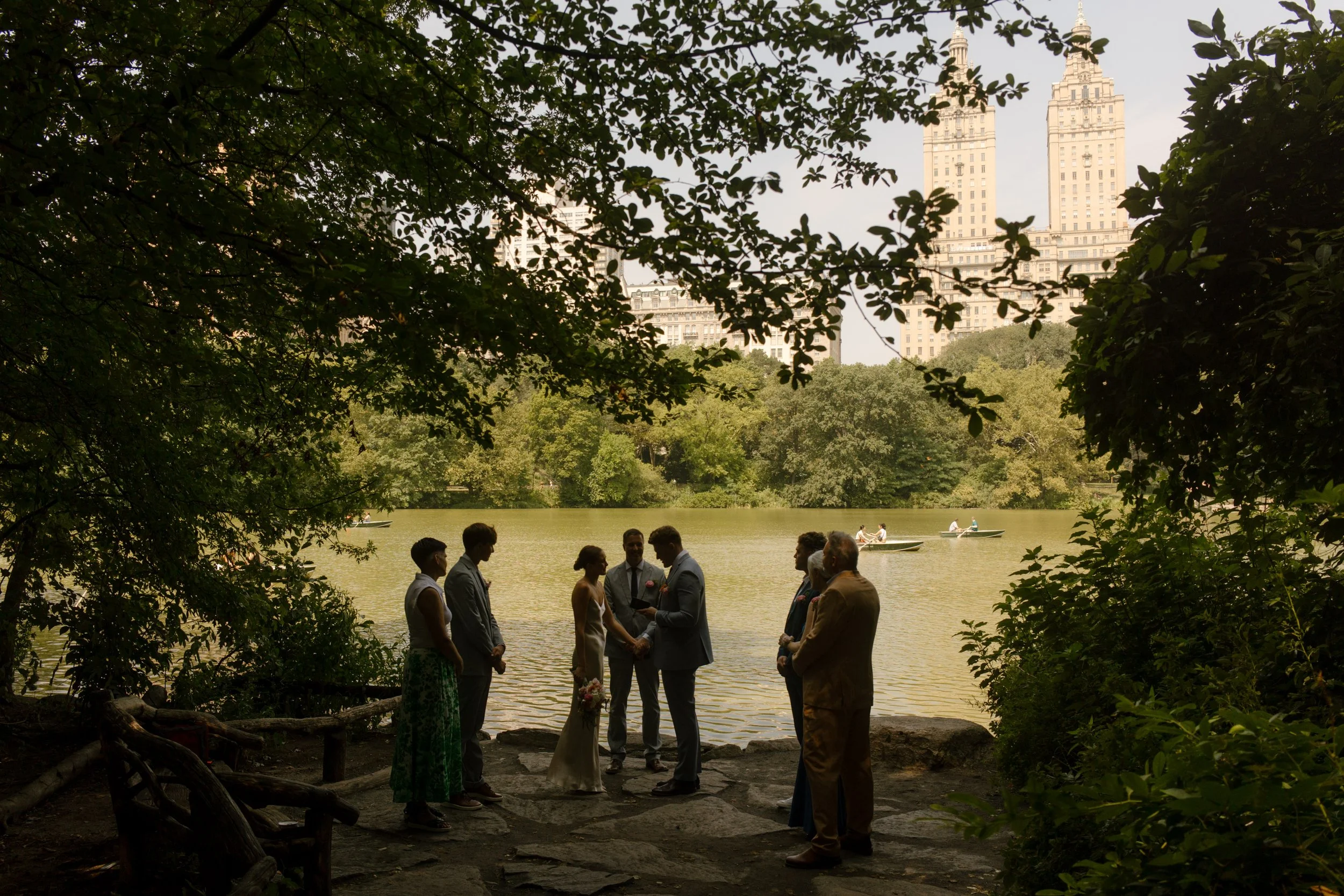 Wide view of an intimate Central Park wedding ceremony with the New York City skyline in the background during the wedding day timeline.