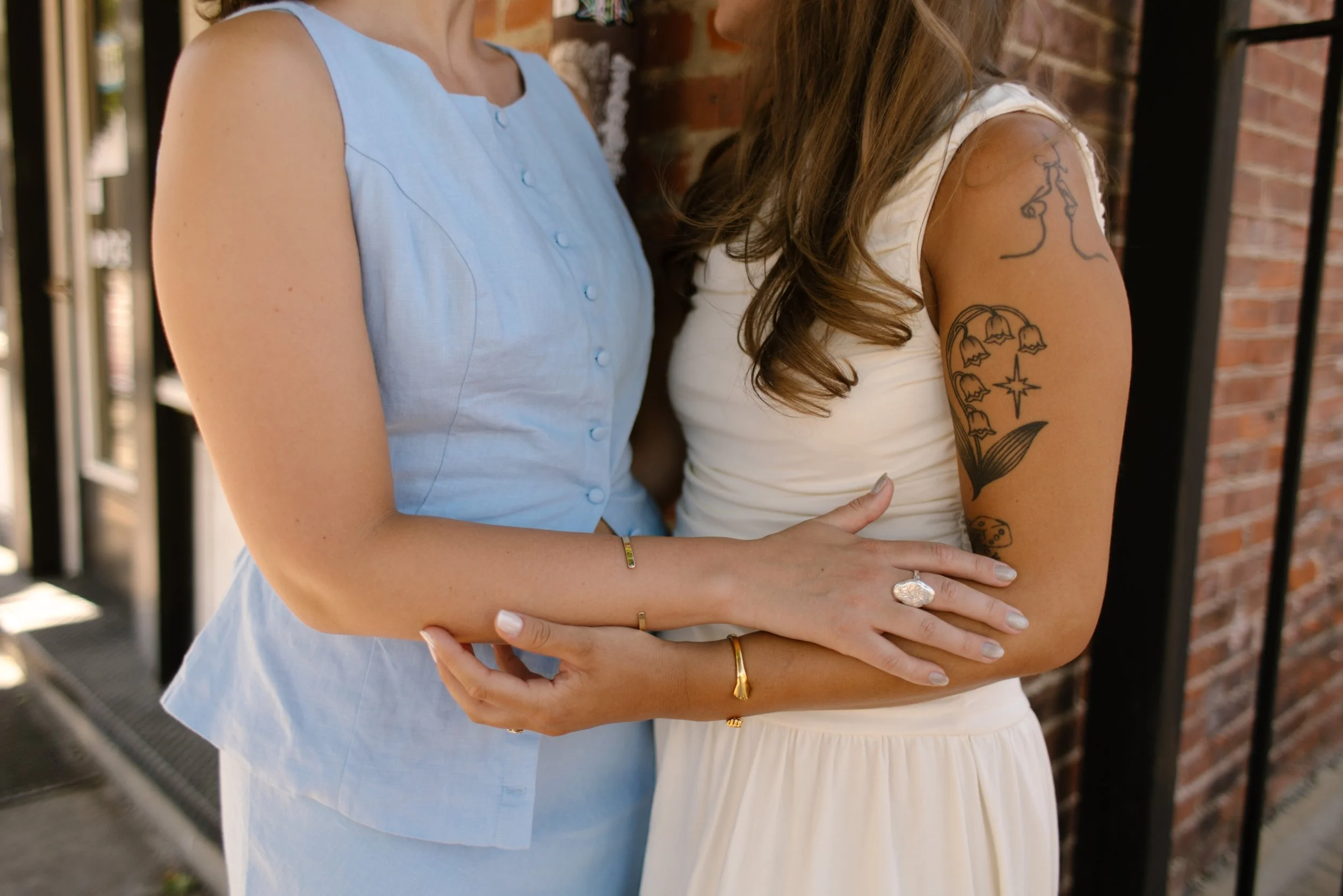 Close-up of two brides embracing, highlighting wedding rings and affectionate connection.