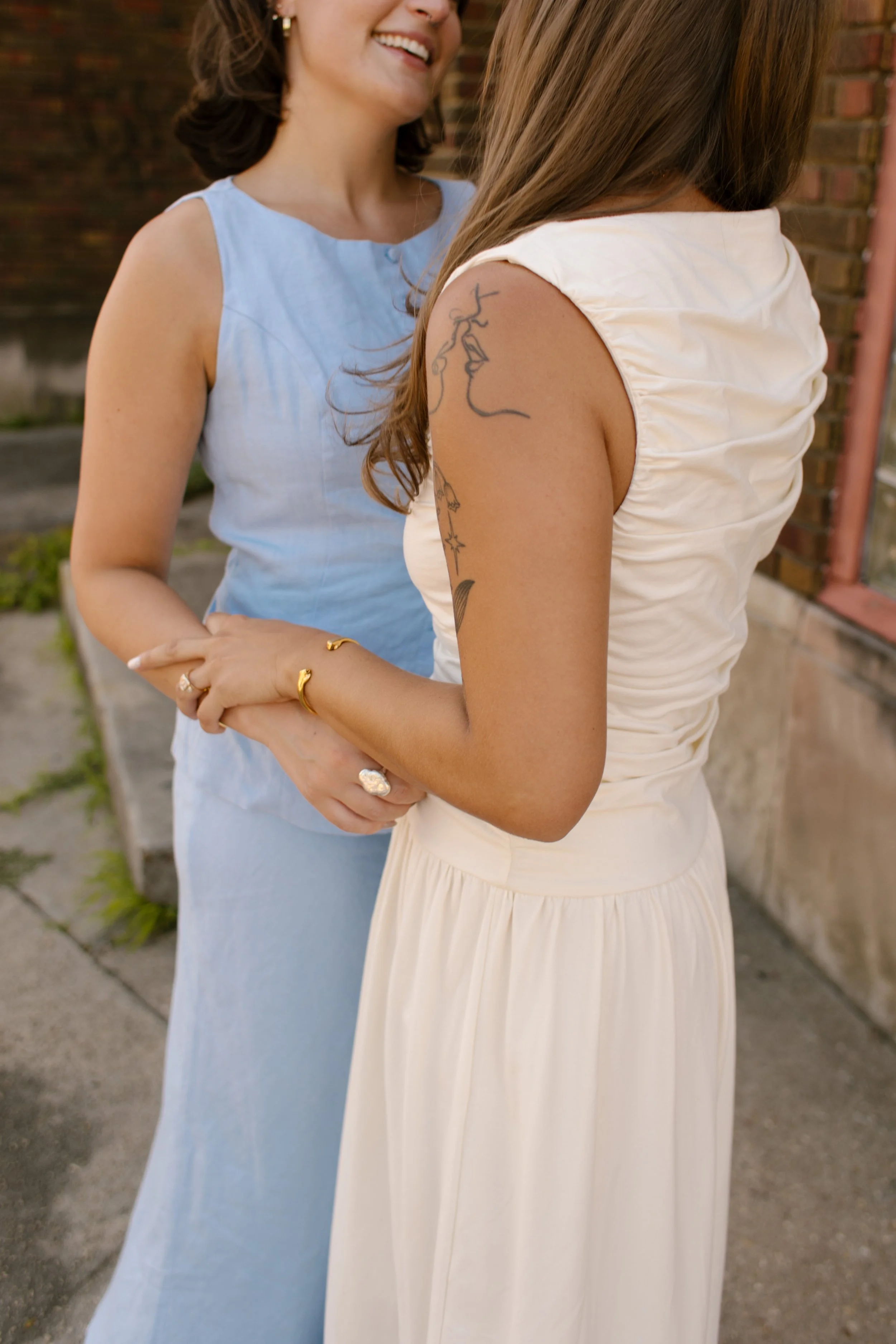 Close-up of two brides holding hands and smiling during a documentary wedding photographer portrait session.