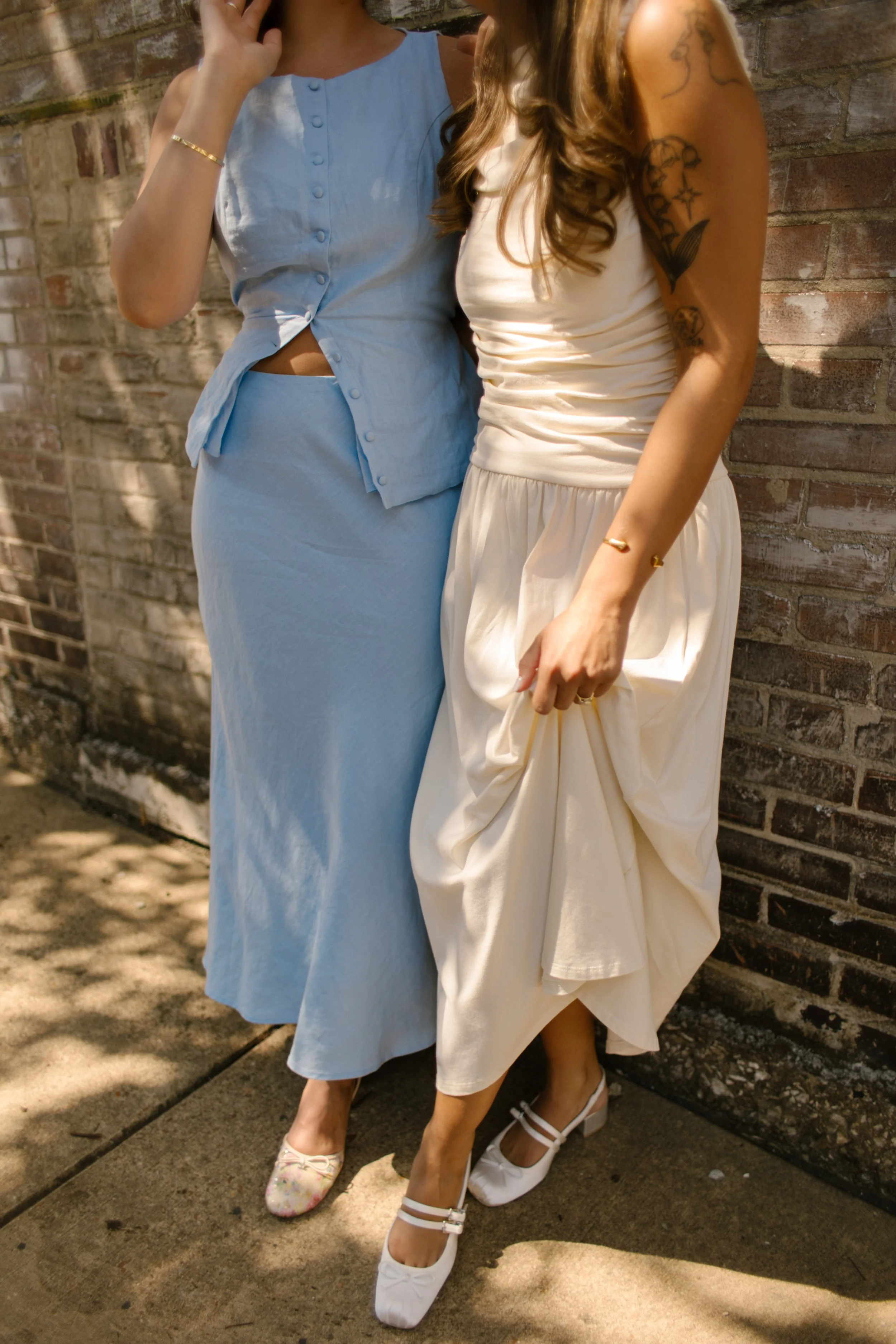 Detail of two brides standing together in modern wedding attire during candid portraits.