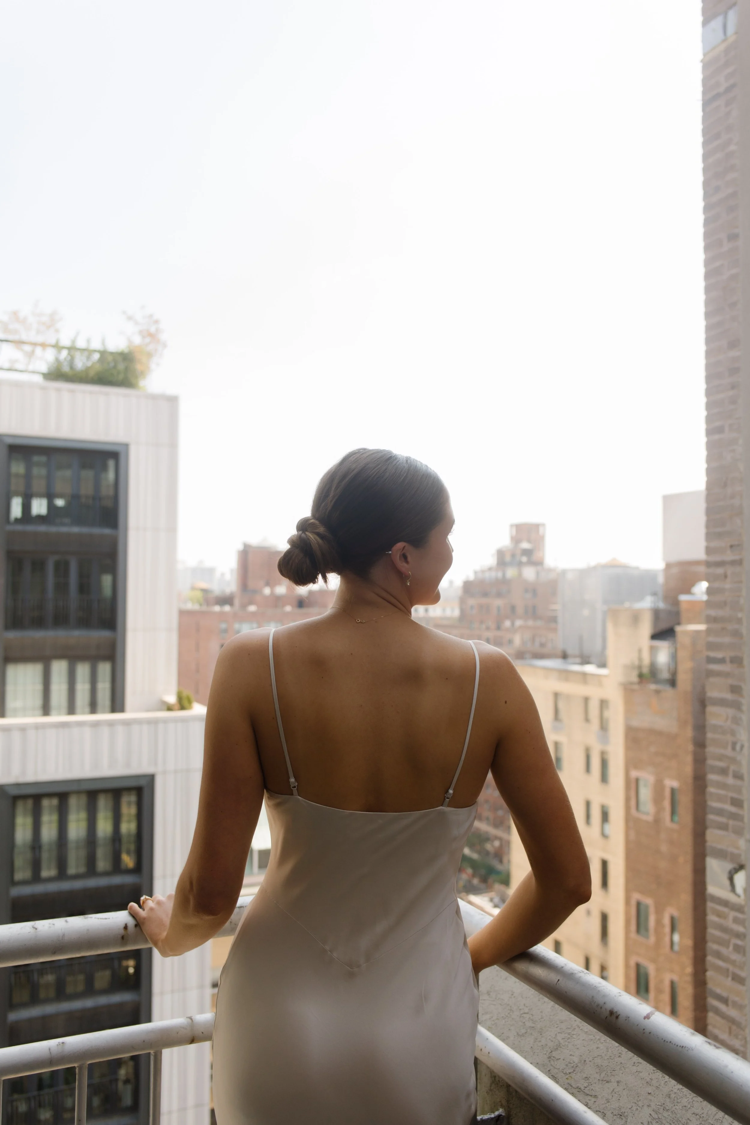 Bride photographed from behind on a balcony with the NYC skyline in the background.