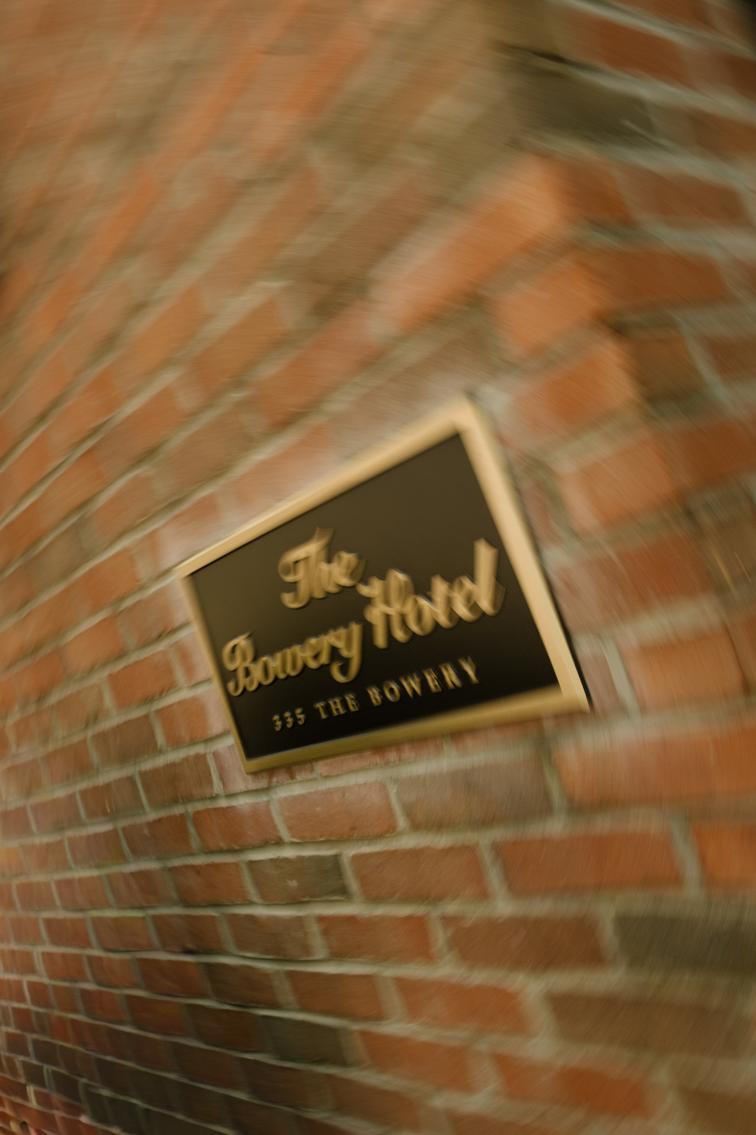Motion-blurred detail of The Bowery Hotel sign against its distinctive brick exterior.