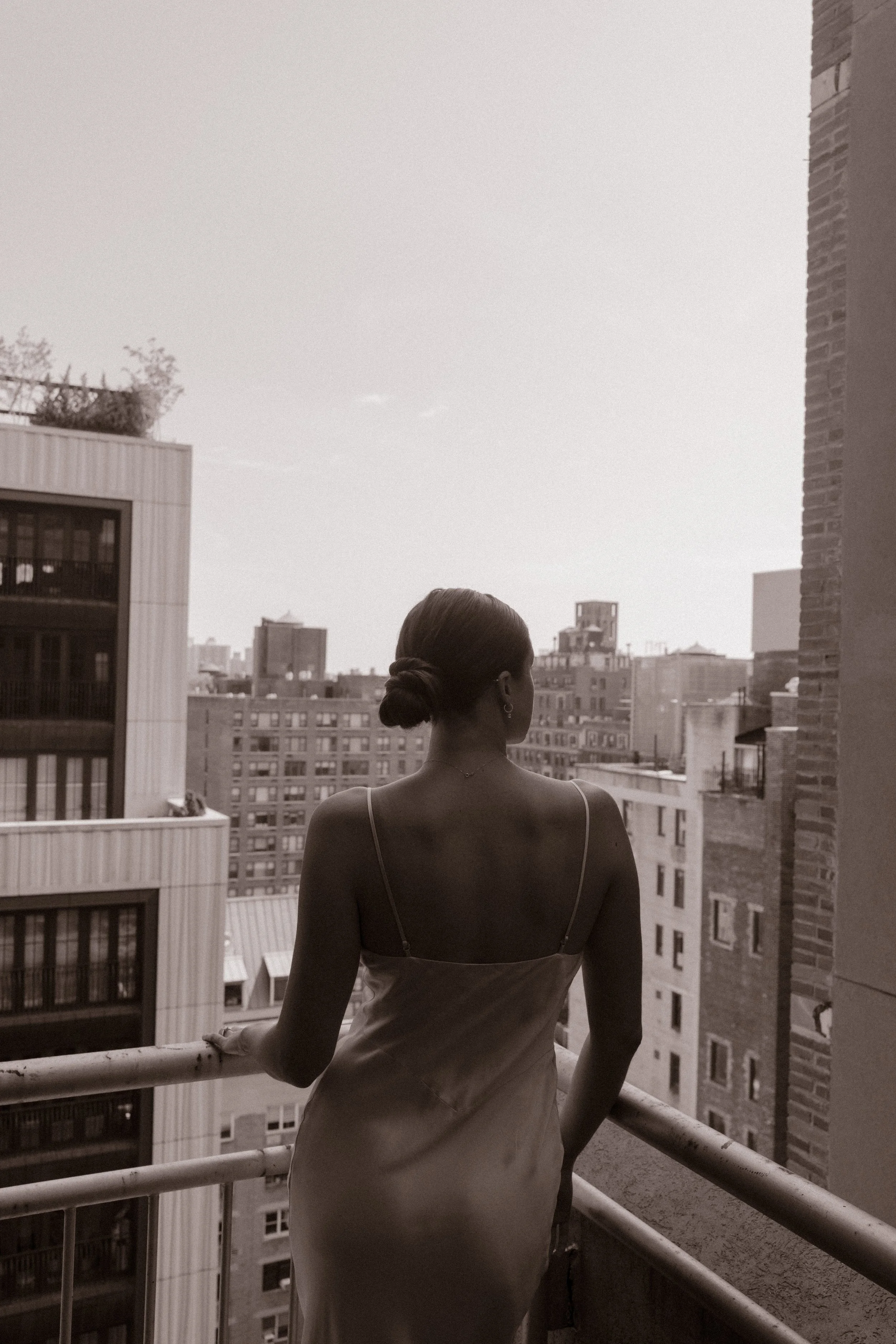 Black-and-white bridal portrait overlooking the NYC skyline from a hotel balcony.