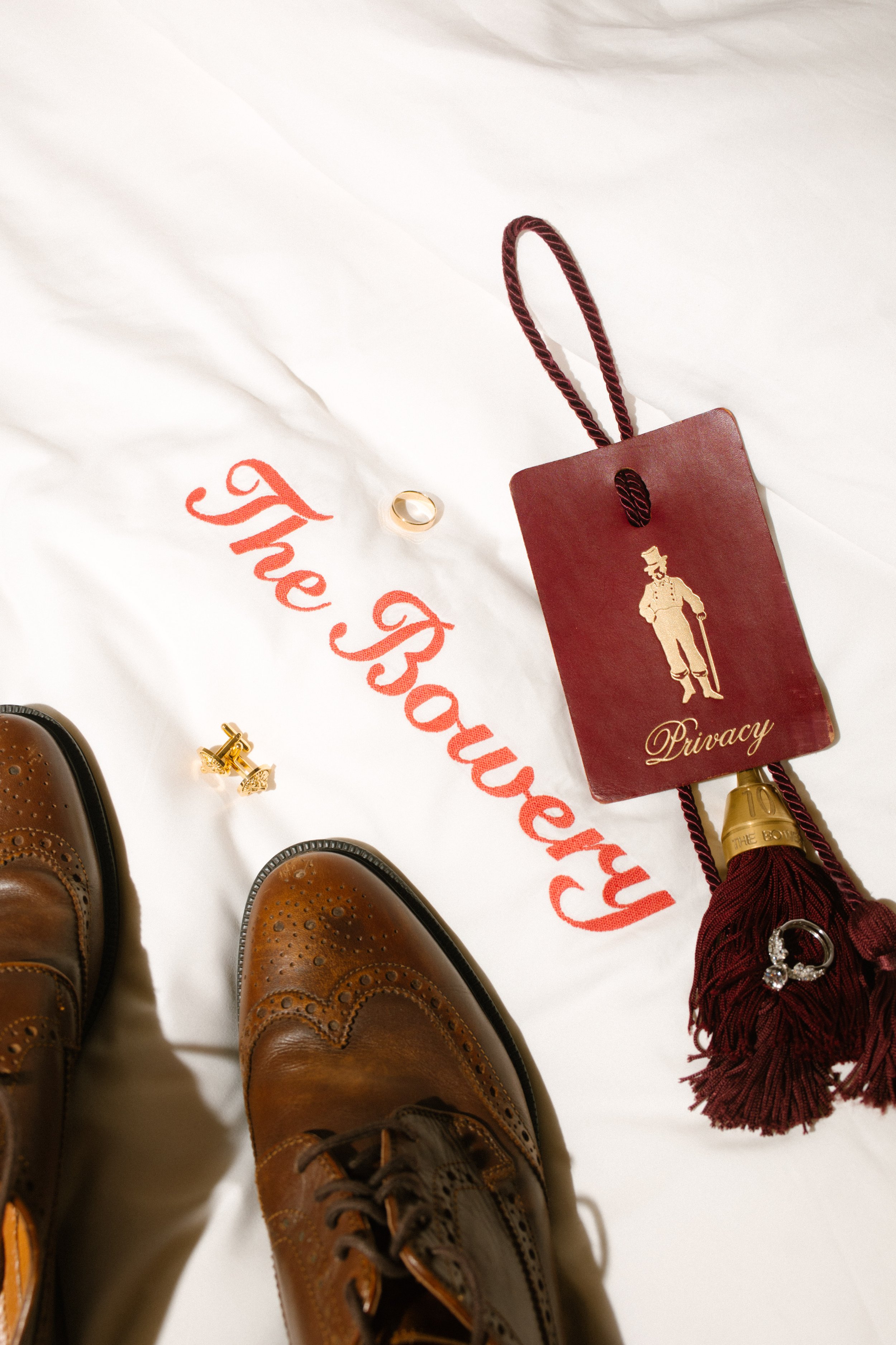 Wedding shoes, rings, cufflinks and Bowery Hotel details arranged on a bed at one of the NYC hotels.