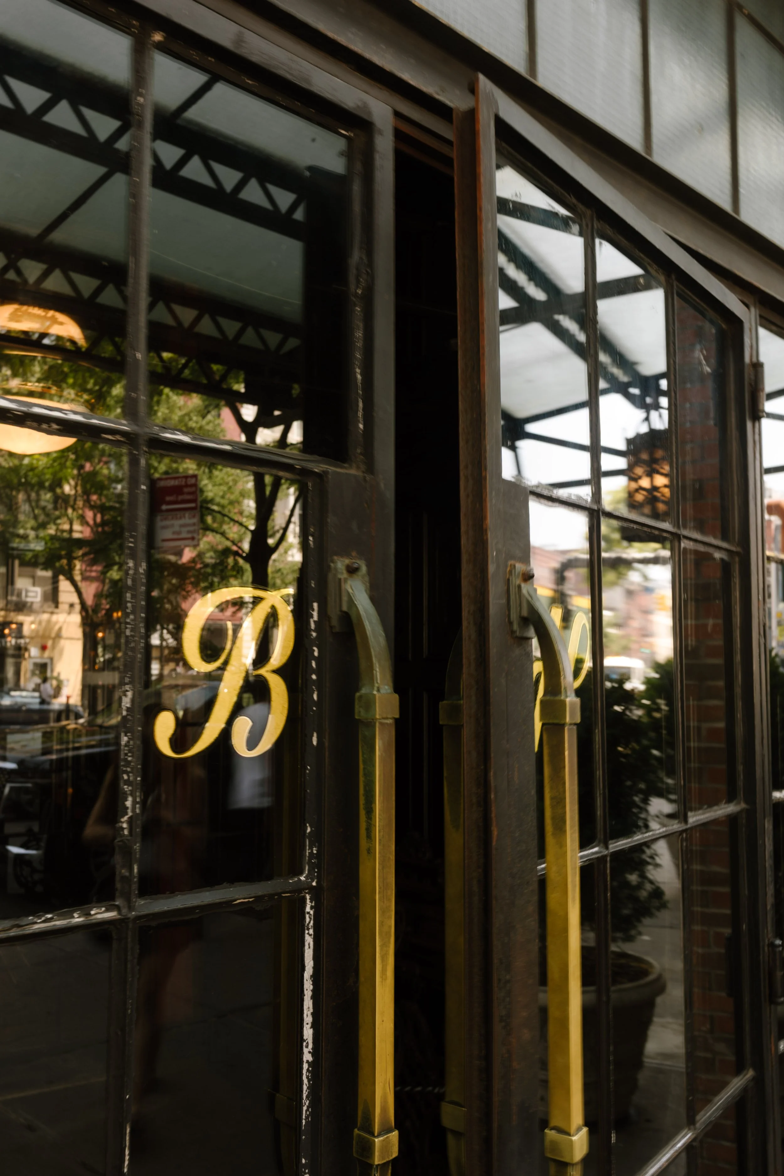 Glass entrance doors with brass handles at The Bowery Hotel, one of the iconic NYC hotels.