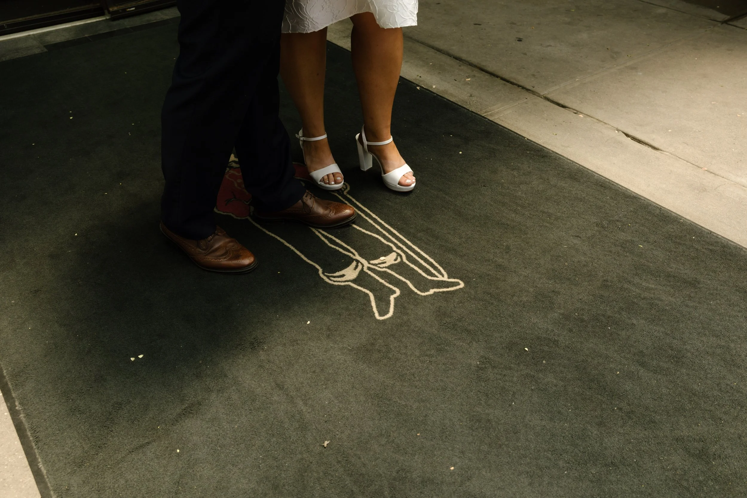 Bride and groom stand together on The Bowery Hotel entrance mat before heading out for their New York wedding day.
