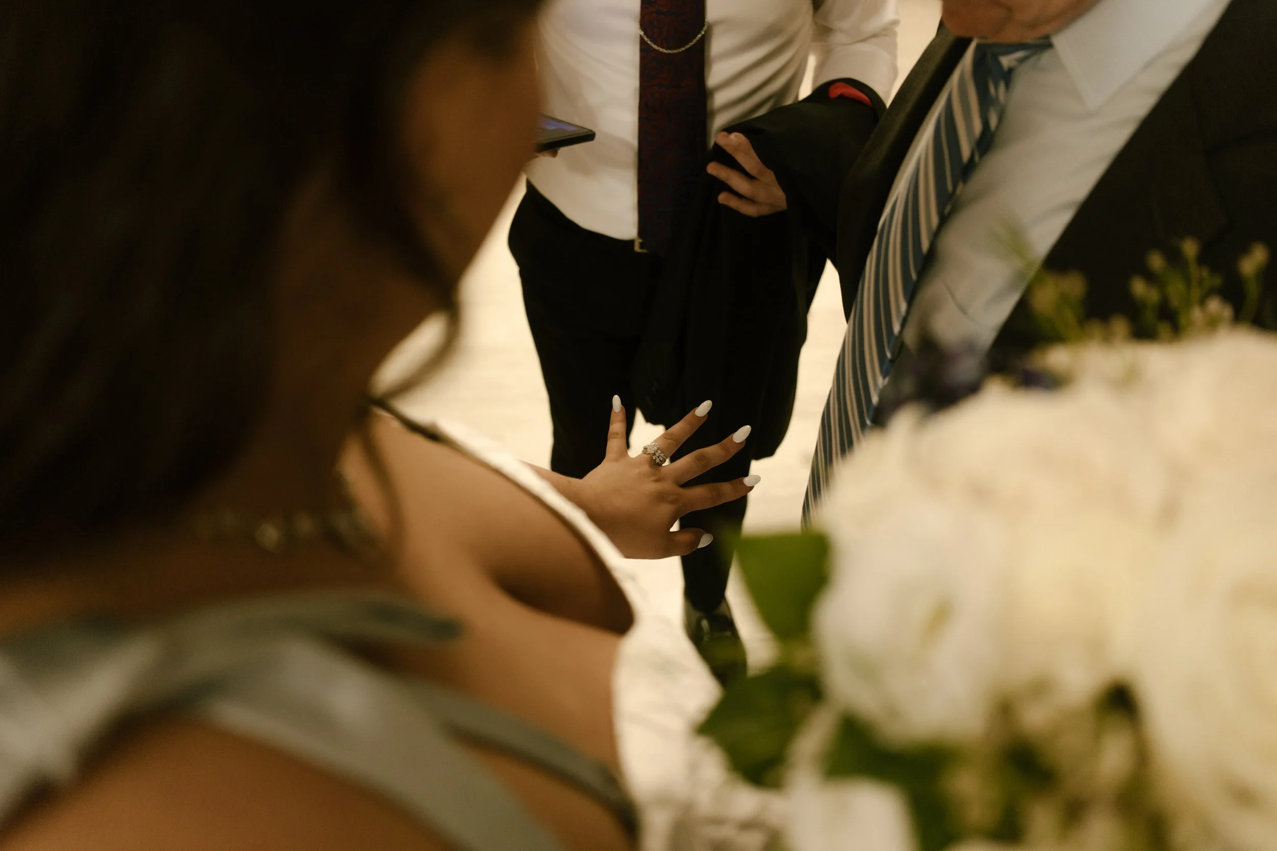 Bride admires her wedding ring while sharing a quiet moment with family during wedding morning preparations.