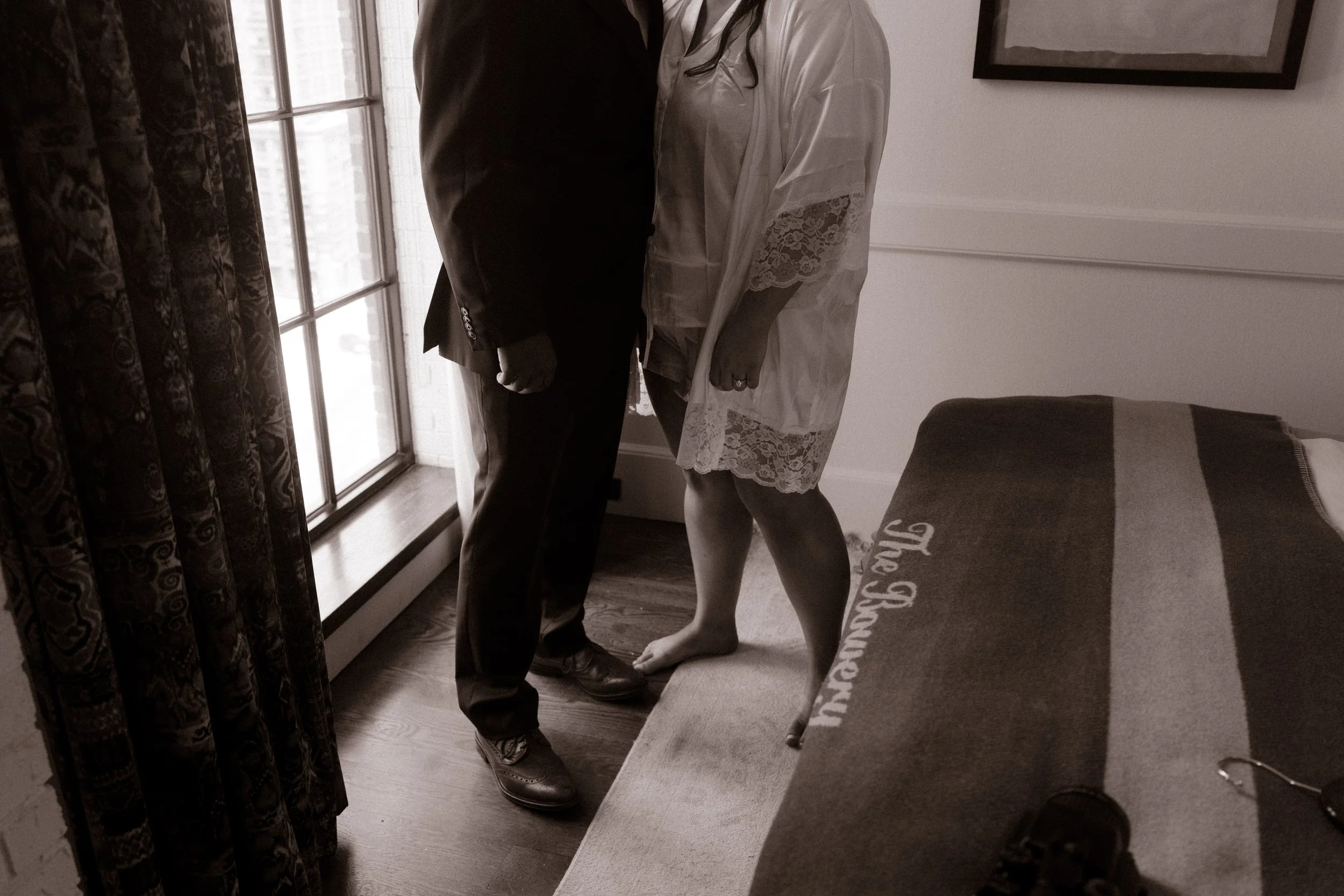 Bride and groom share a quiet moment by the window inside one of the charming NYC hotels before their wedding ceremony.