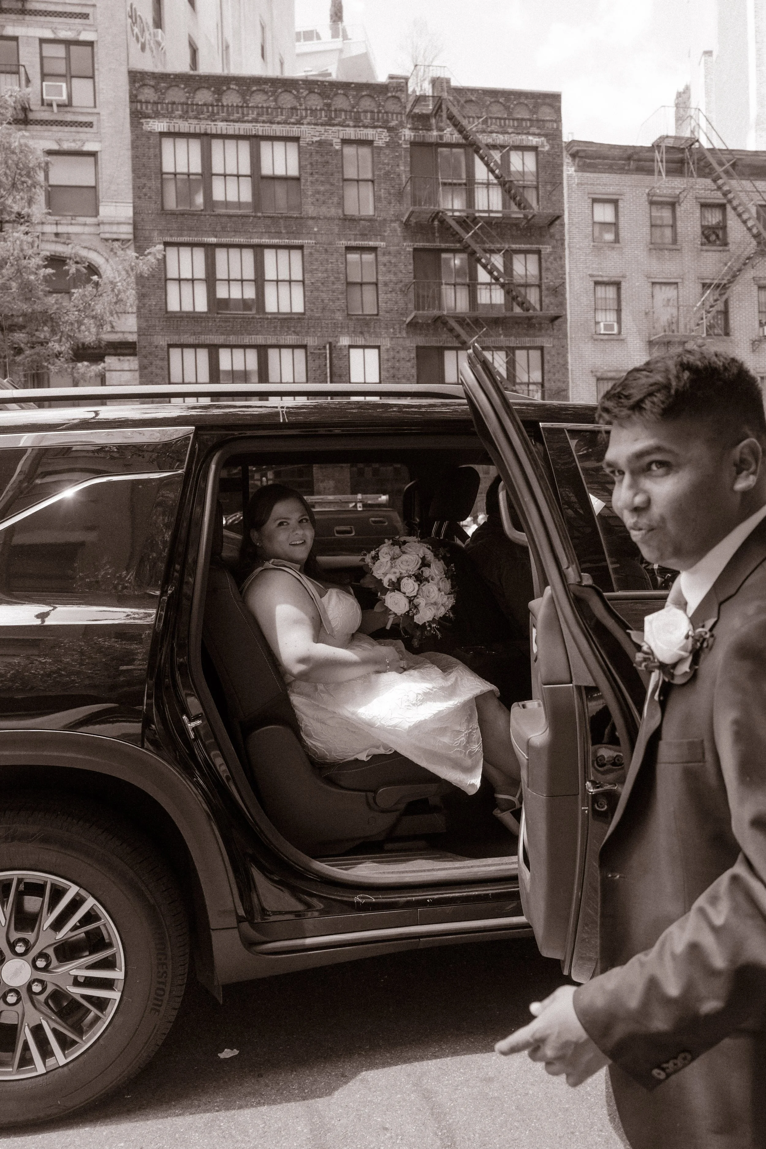 Bride smiles from the backseat of a car as the couple leaves NYC hotels to begin their New York wedding day.