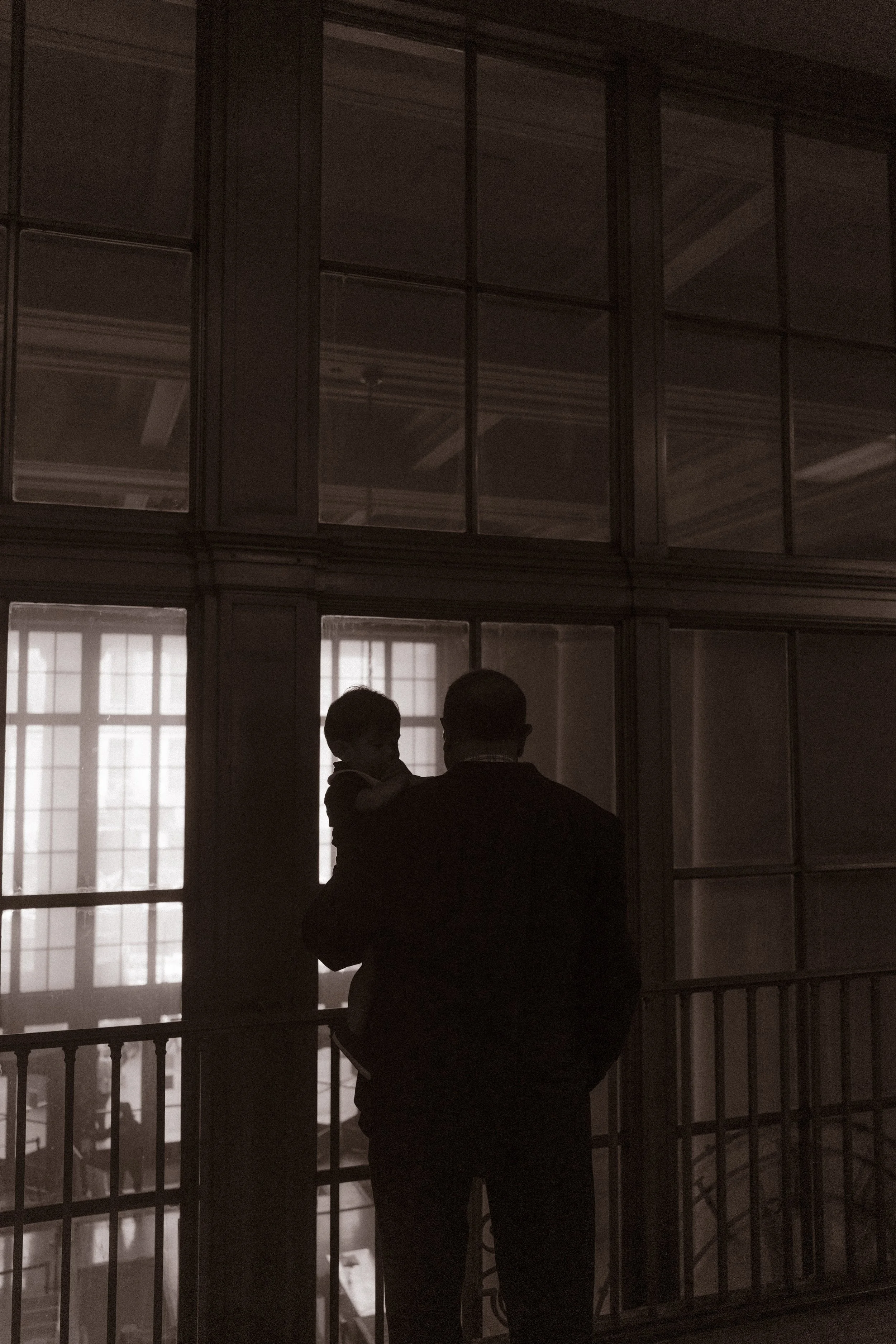 Parent holds a child while overlooking the dramatic interior of one of NYC hotels during a quiet wedding morning.
