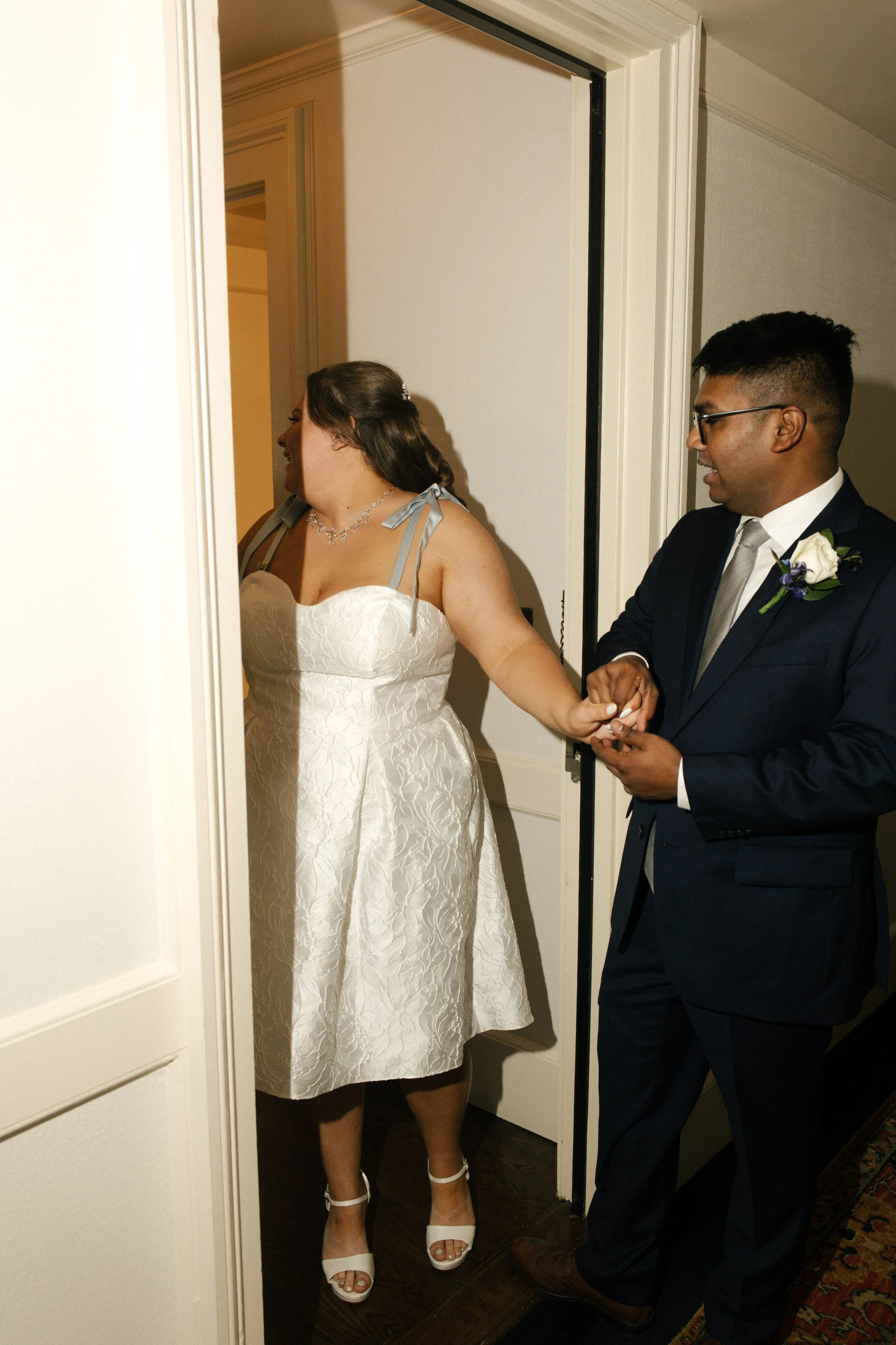 Newlyweds holding hands in a doorway while getting ready at one of the NYC hotels.
