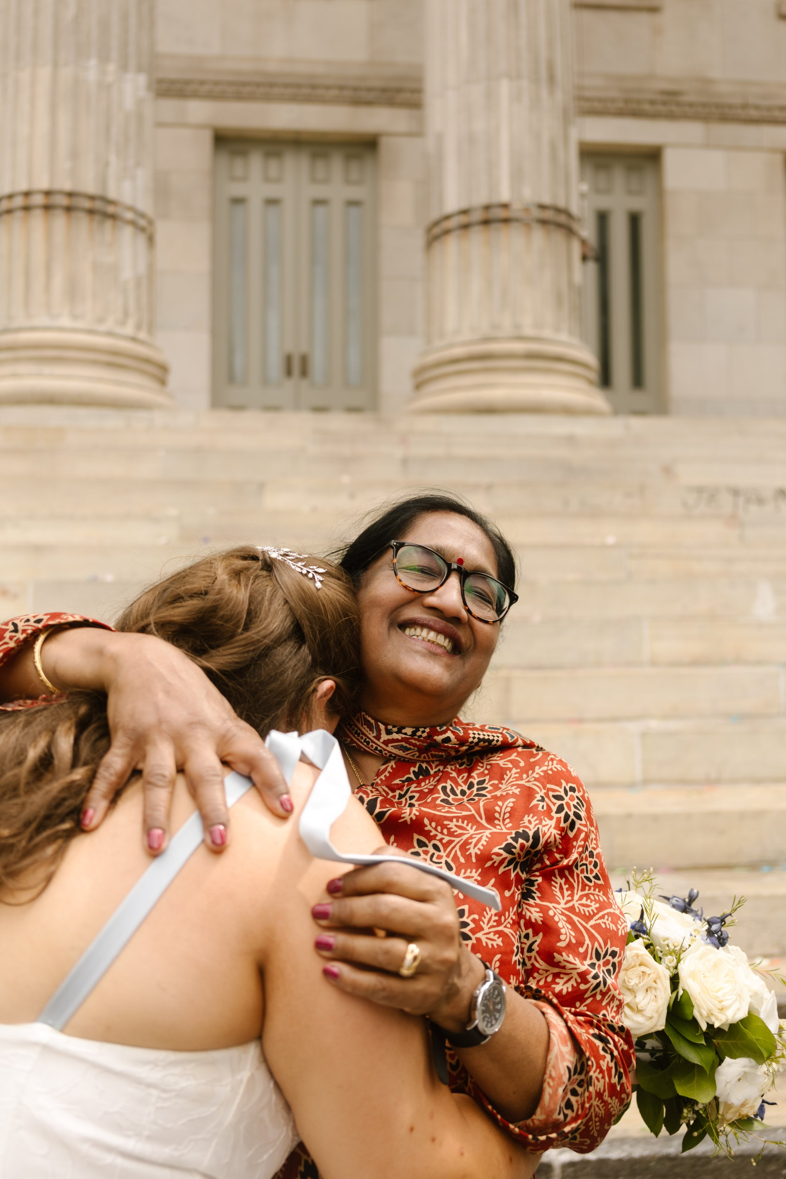 Emotional hug between a bride and her mother in law outside City Hall following an intimate New York wedding ceremony.