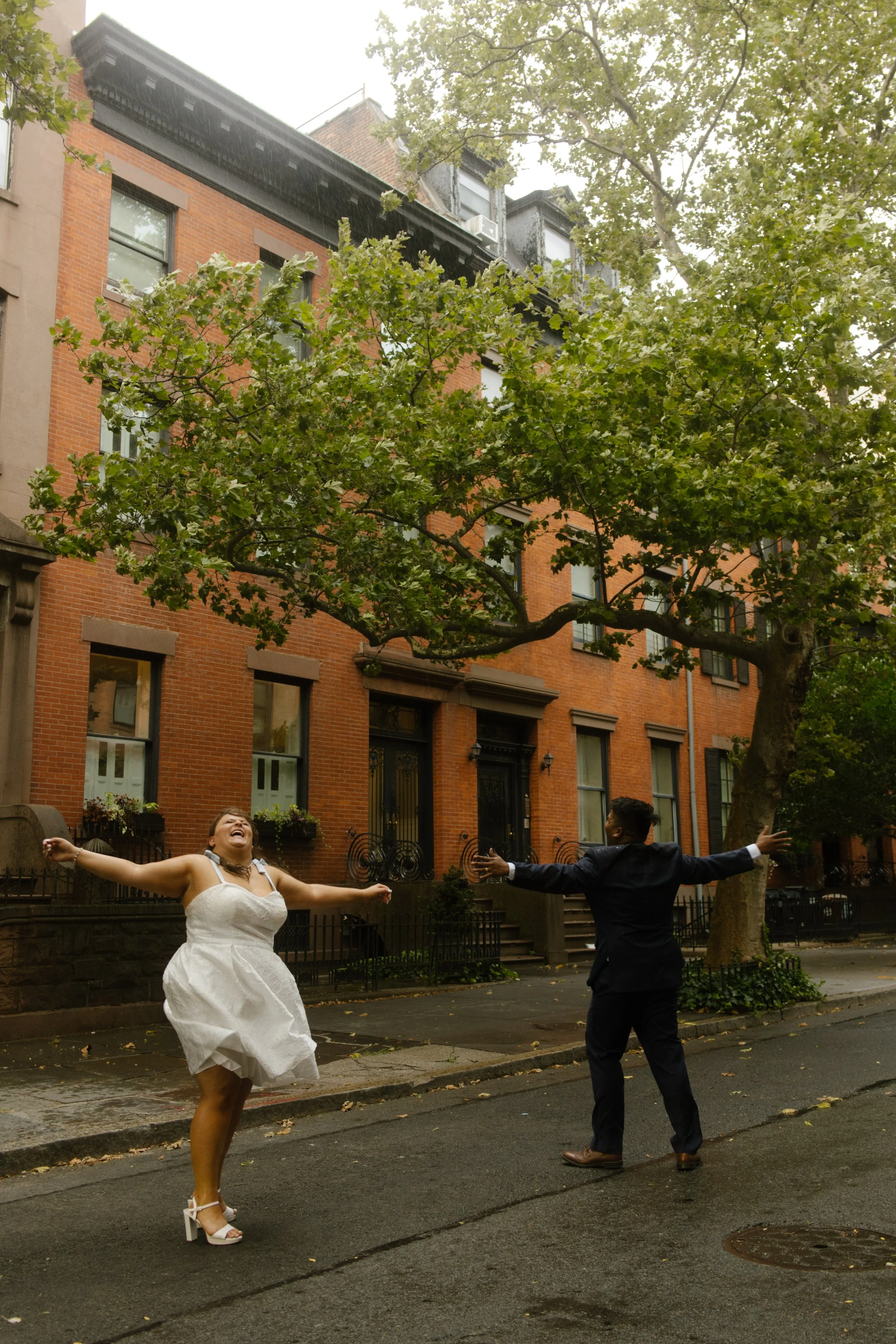 Rainy wedding portraits in a quiet brownstone neighborhood near NYC hotels with a couple embracing the weather together.