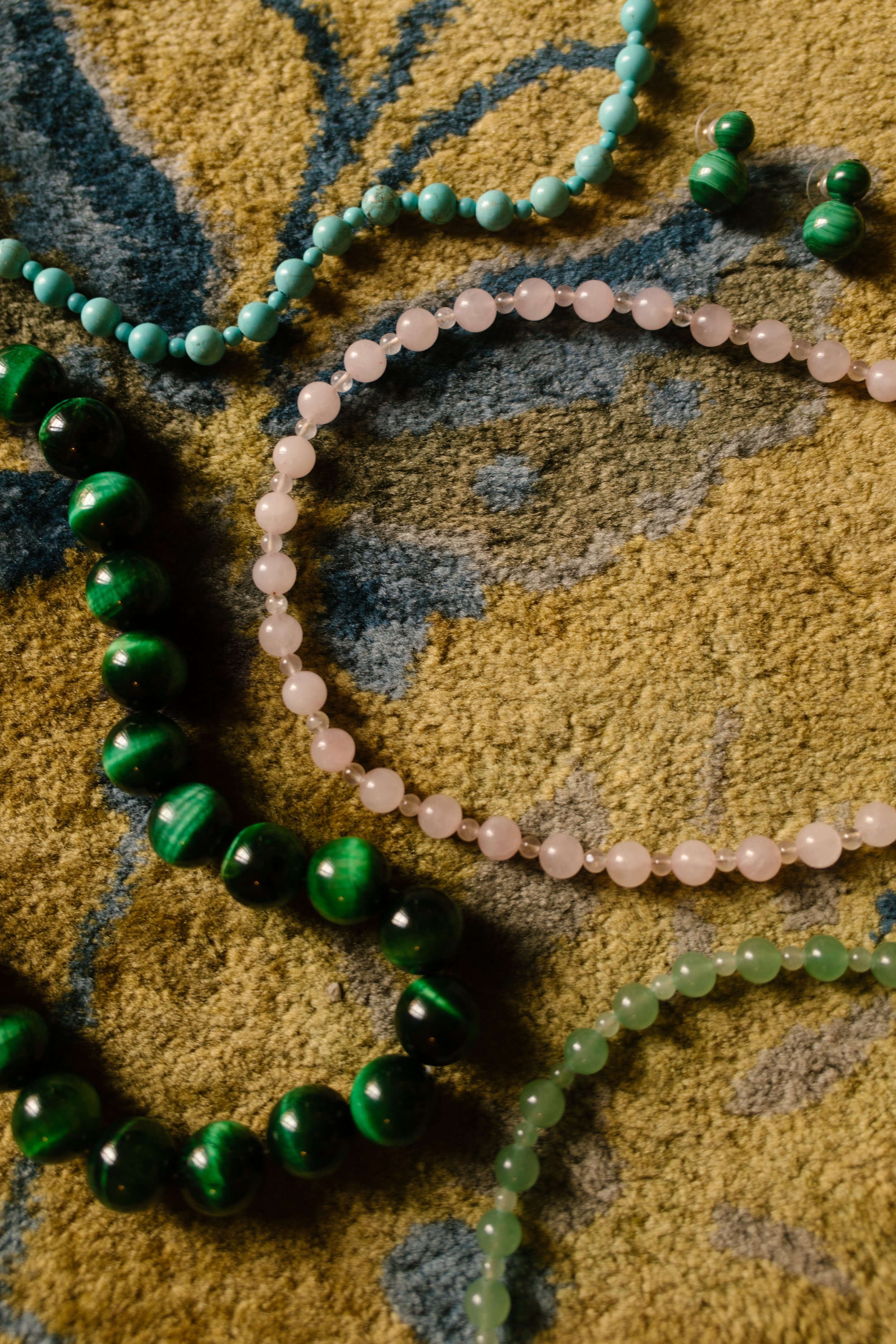 Colorful gemstone necklaces and vintage-inspired jewelry arranged on a patterned rug as meaningful wedding morning details.