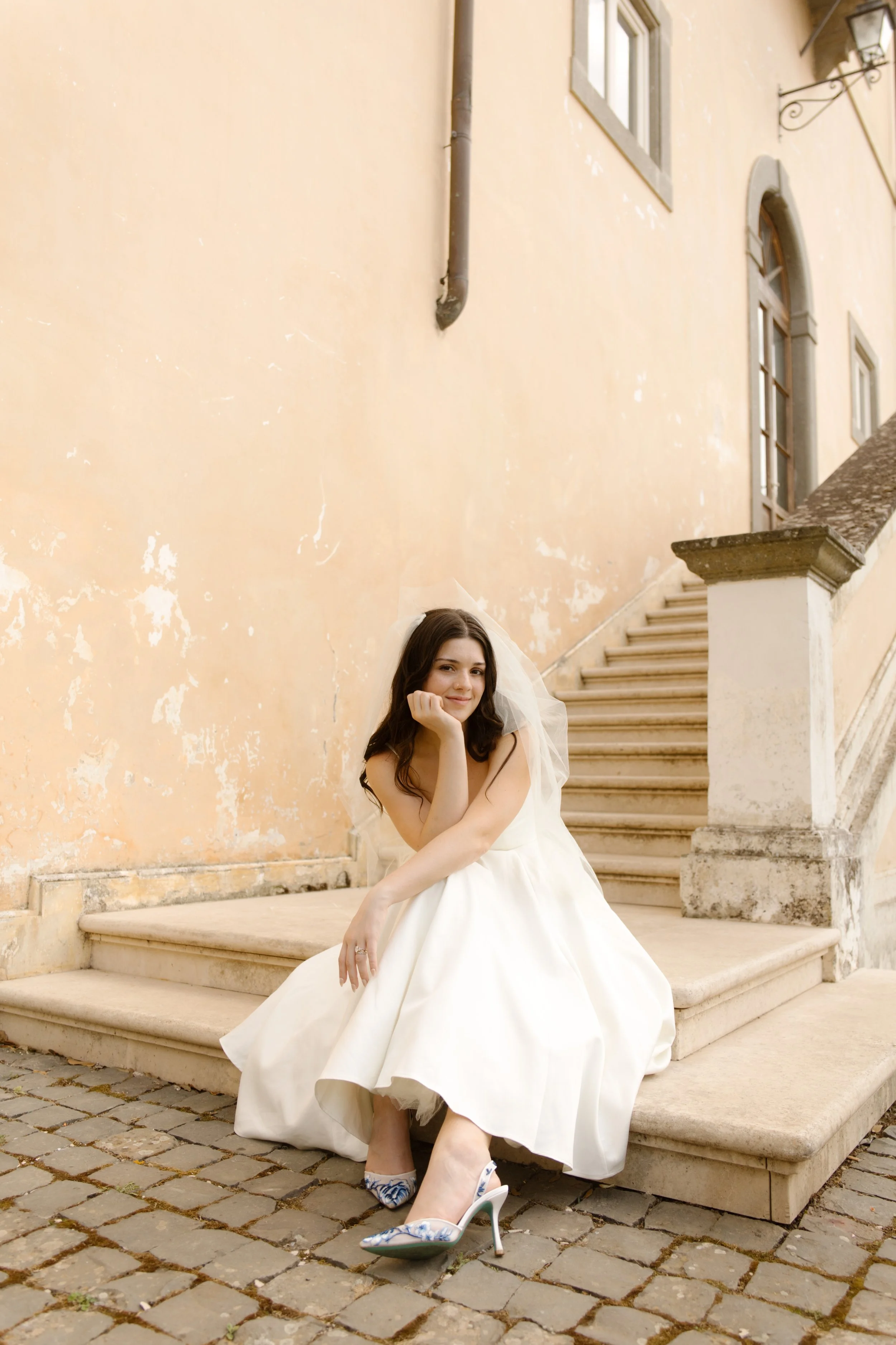 Bride sitting on stone steps in her wedding dress during a Multi-Day Destination Wedding celebration