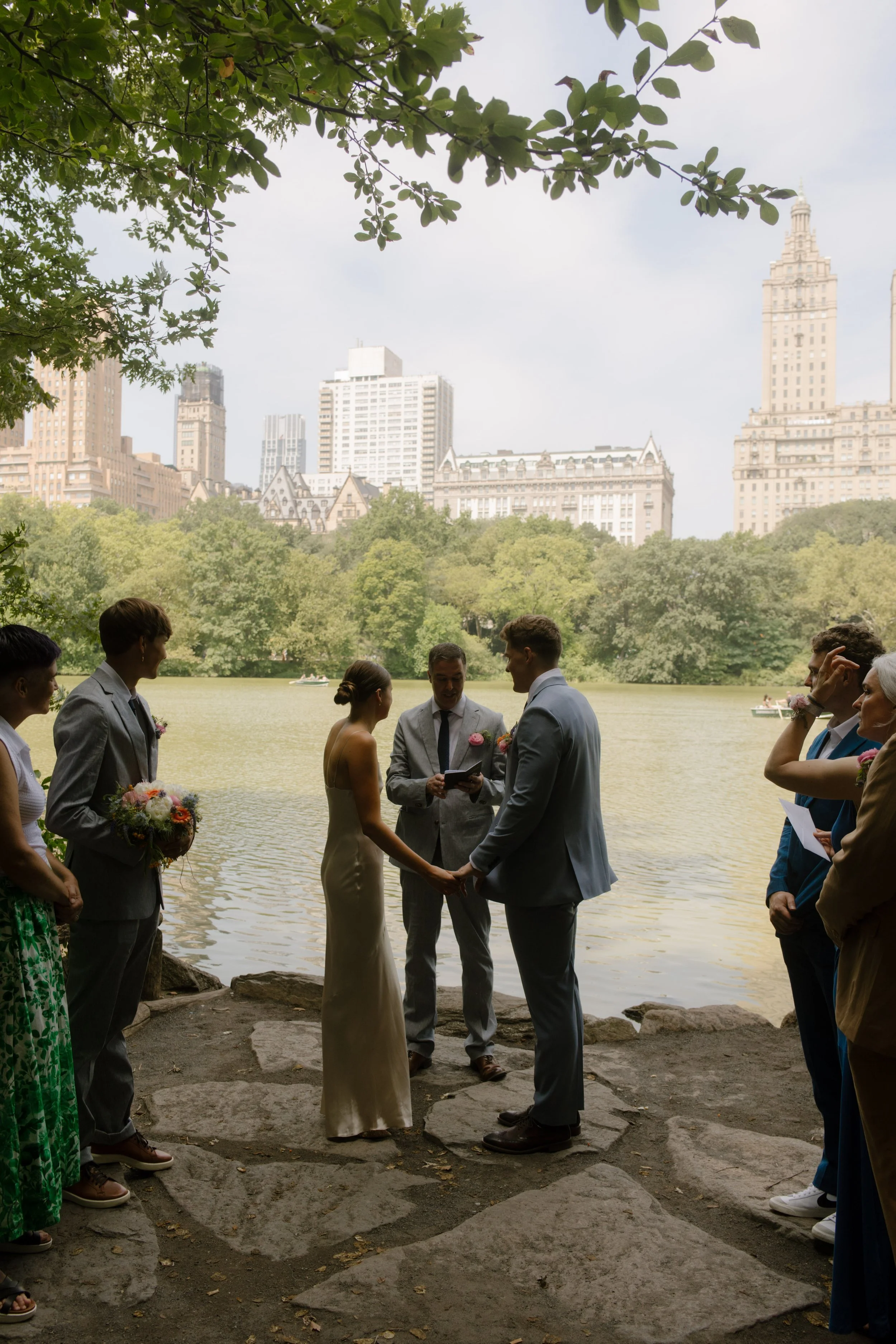 Intimate outdoor wedding ceremony beside the lake in Central Park with the New York City skyline in the background