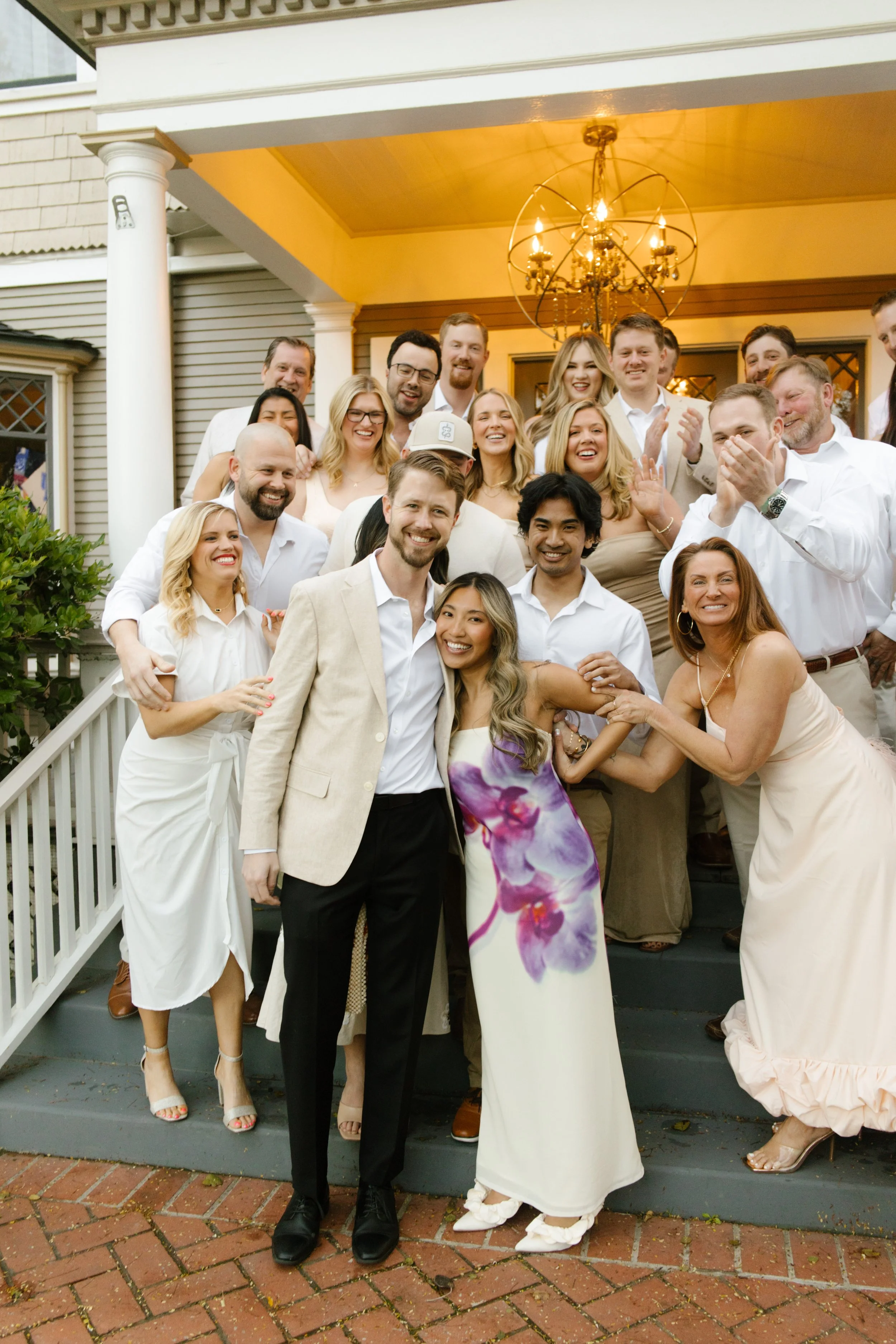 Couple surrounded by friends and family during a relaxed welcome party gathering at a historic home