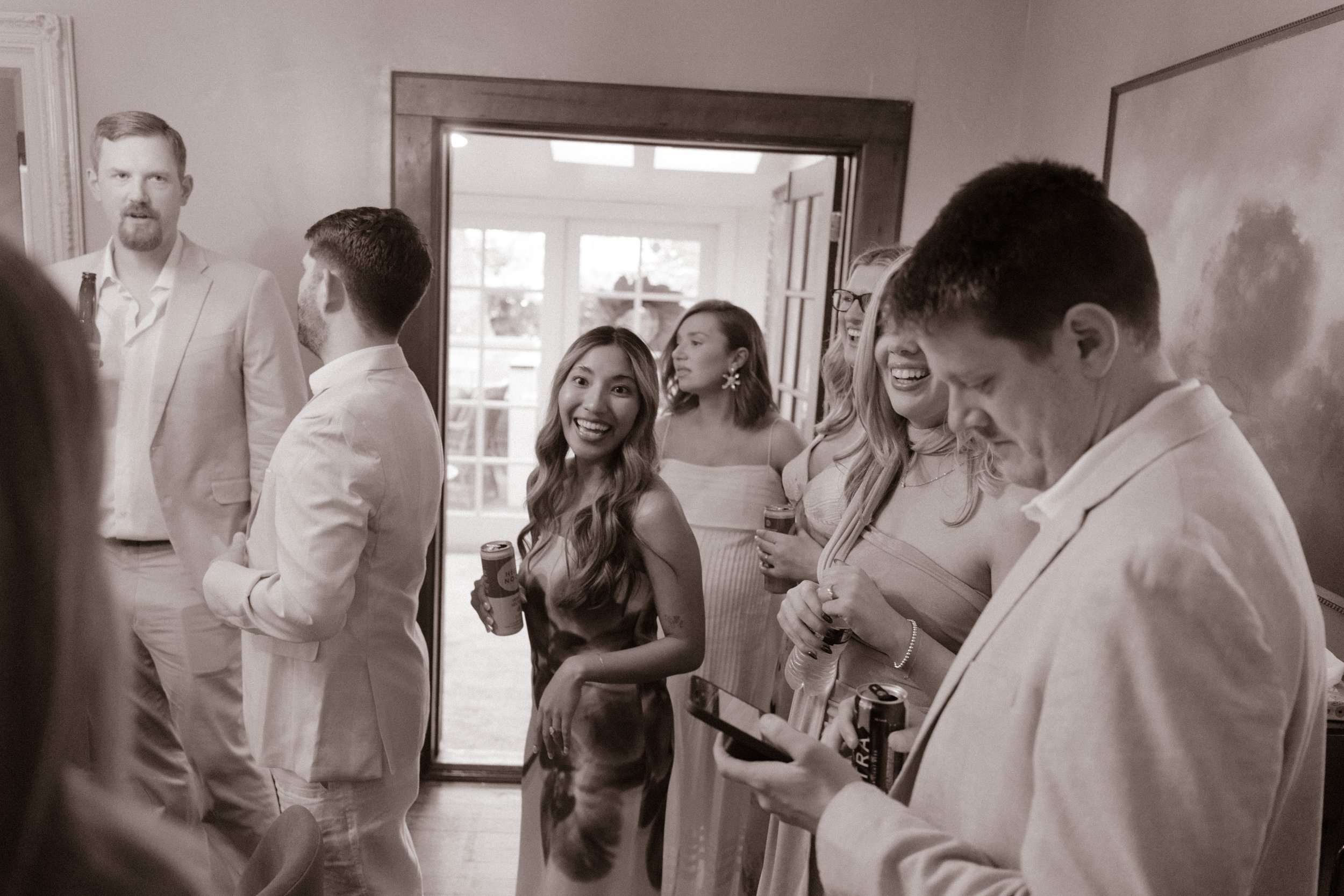 Candid black-and-white photo of wedding guests laughing and spending time together during a relaxed weekend celebration