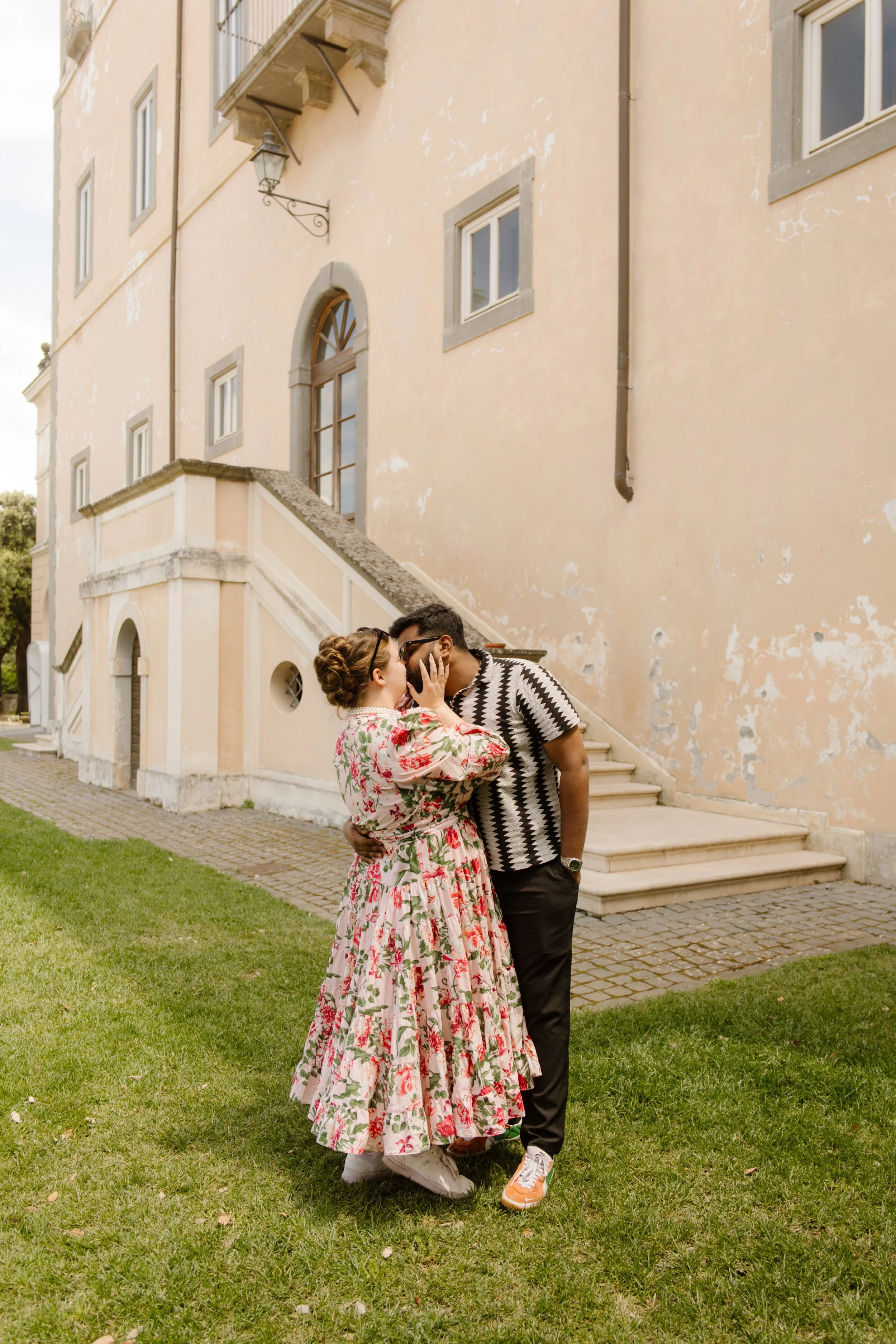 Couple sharing a kiss outside a historic Italian villa during a relaxed destination wedding weekend