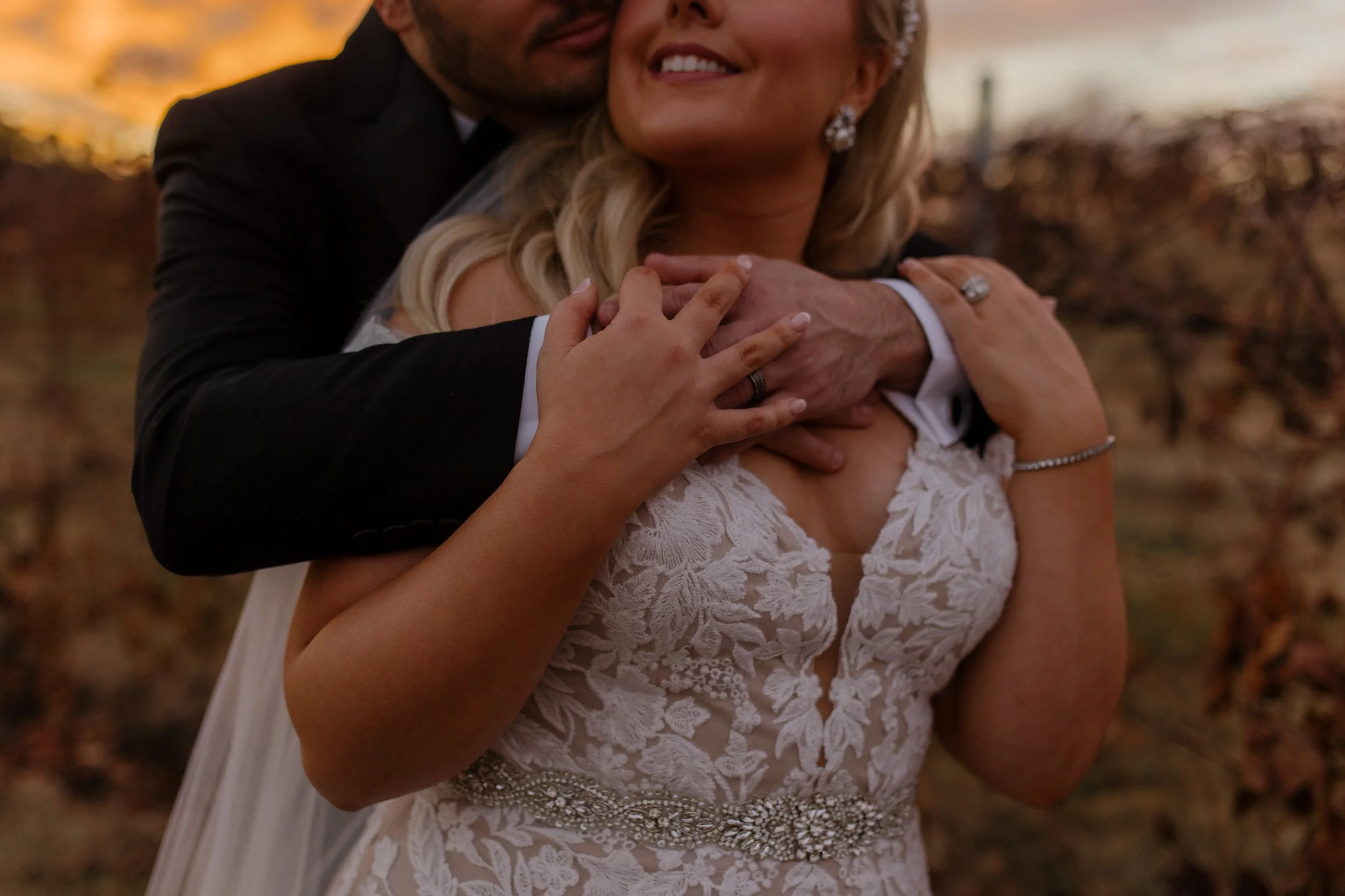 Romantic close-up of a bride and groom embracing in a vineyard at sunset