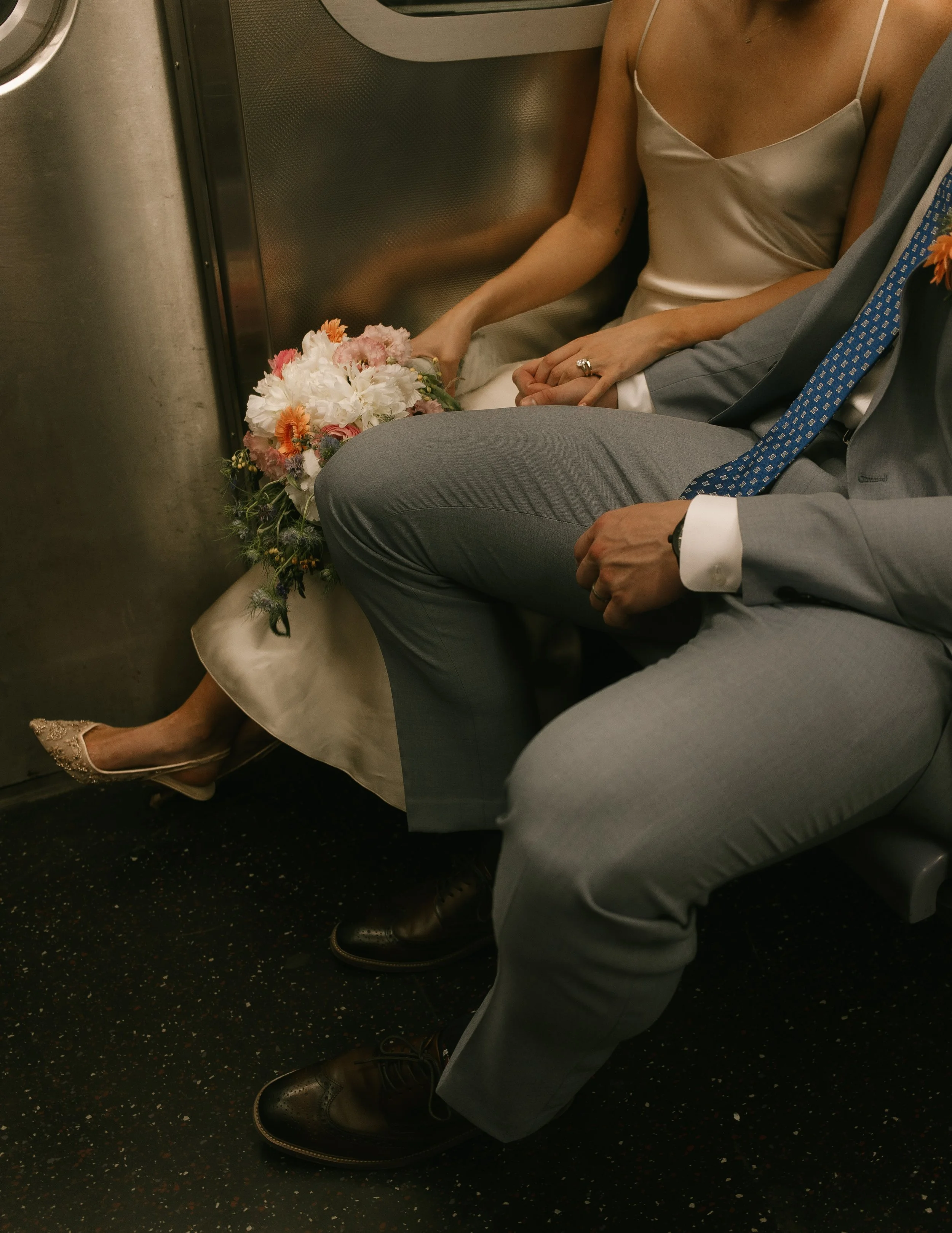 Candid wedding detail of a bride holding her colorful bouquet while riding the New York City subway