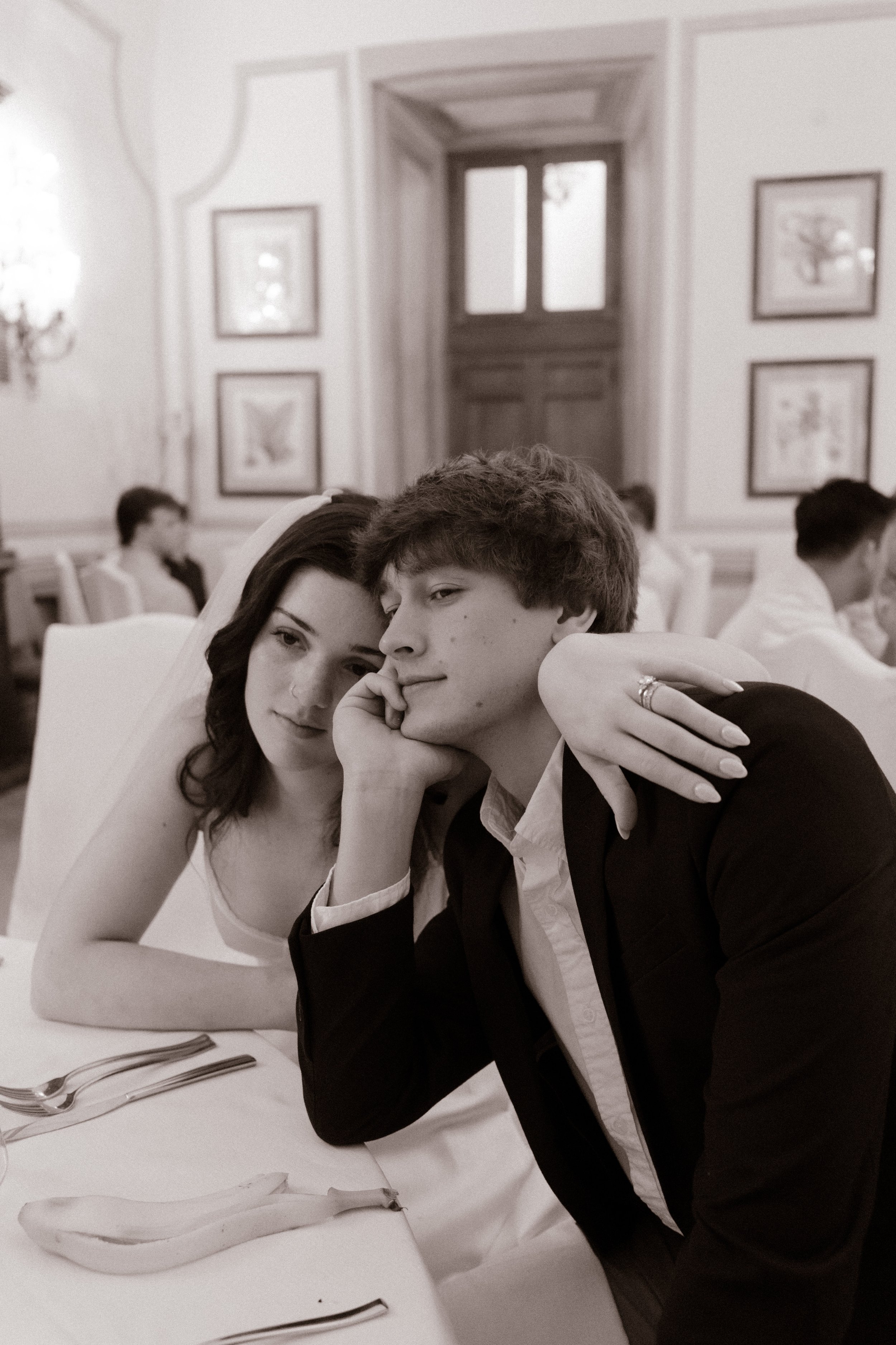 Candid black-and-white portrait of a newlywed couple relaxing together during their wedding reception