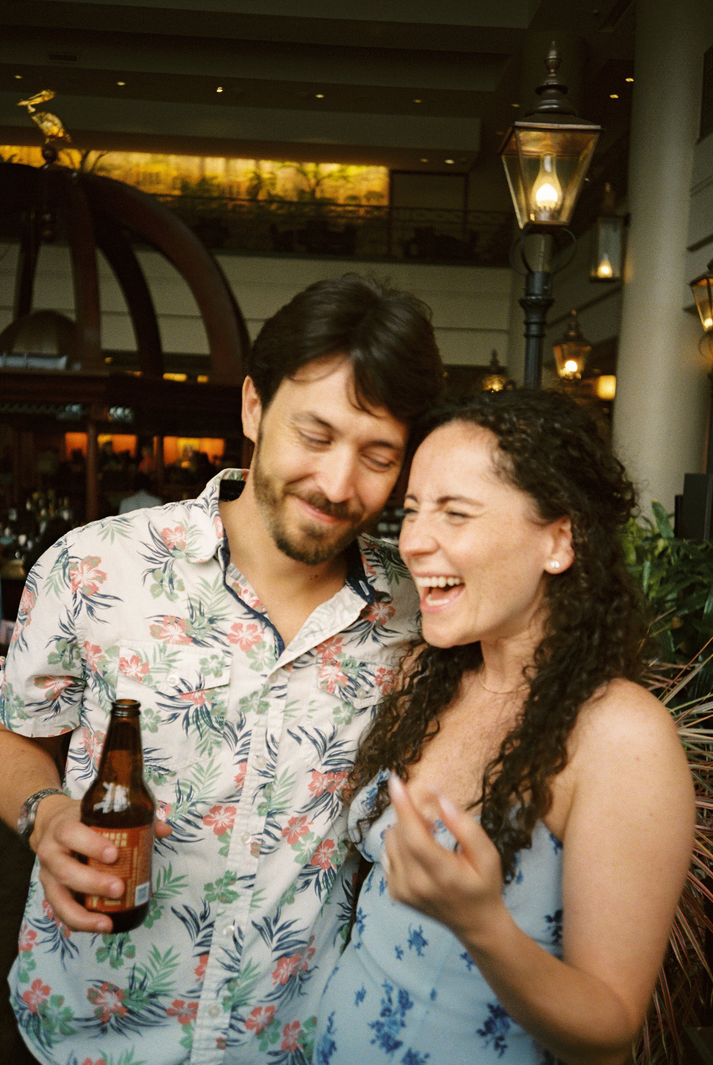 Couple sharing a candid laugh together while mingling with guests at their rehearsal dinner.