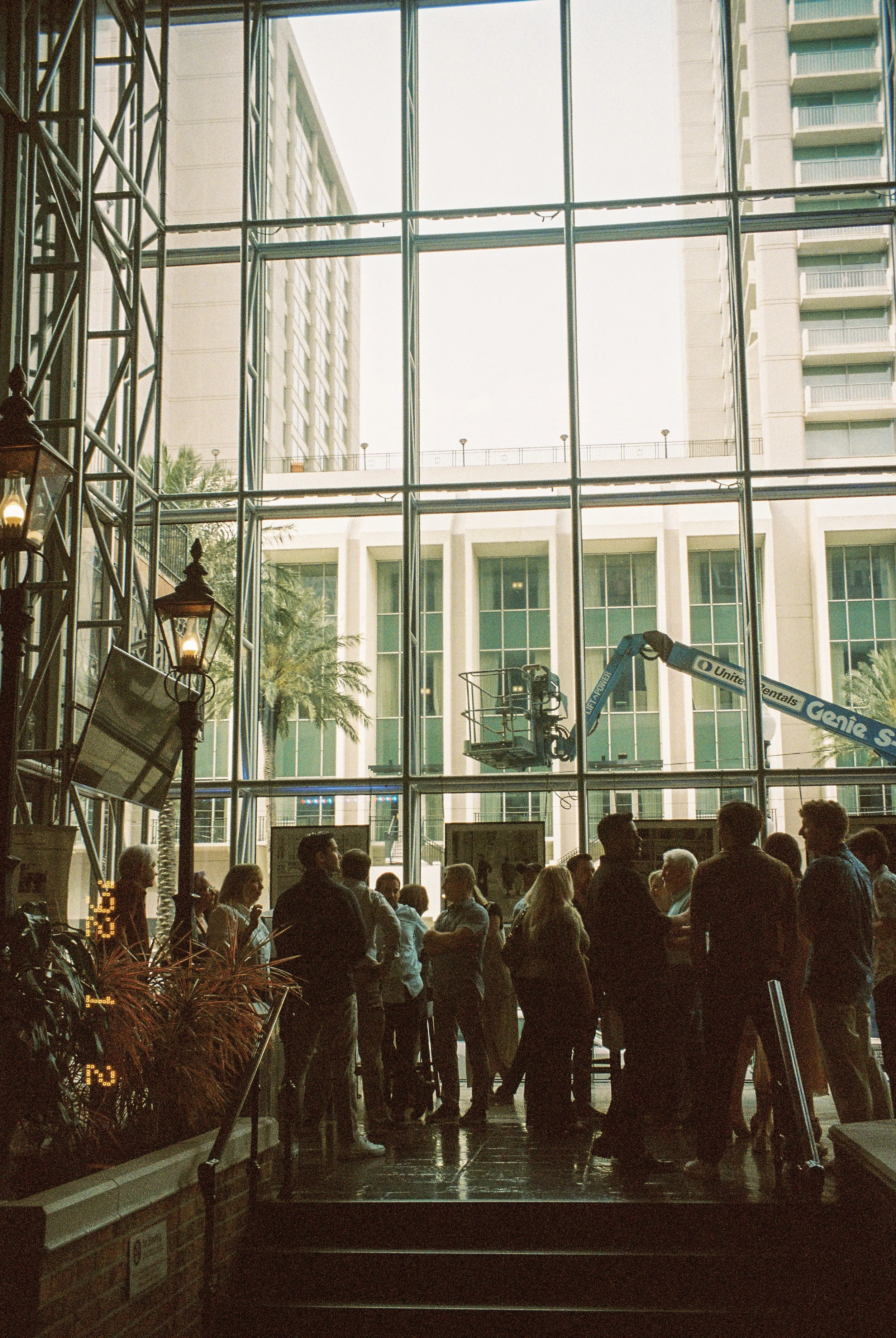 Guests gathering and mingling inside a bright atrium before an evening celebration.